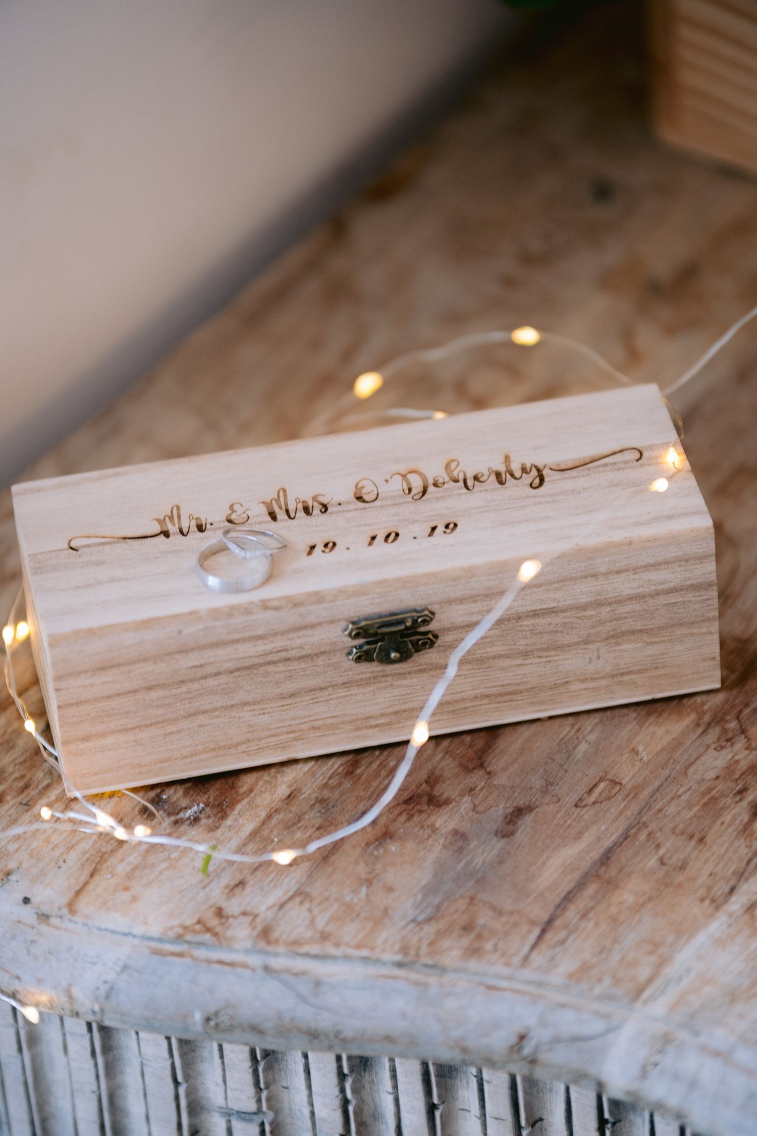 Personalized wooden wine box engraved with Mr. & Mrs. DoHerty wedding date, decorated with fairy lights.