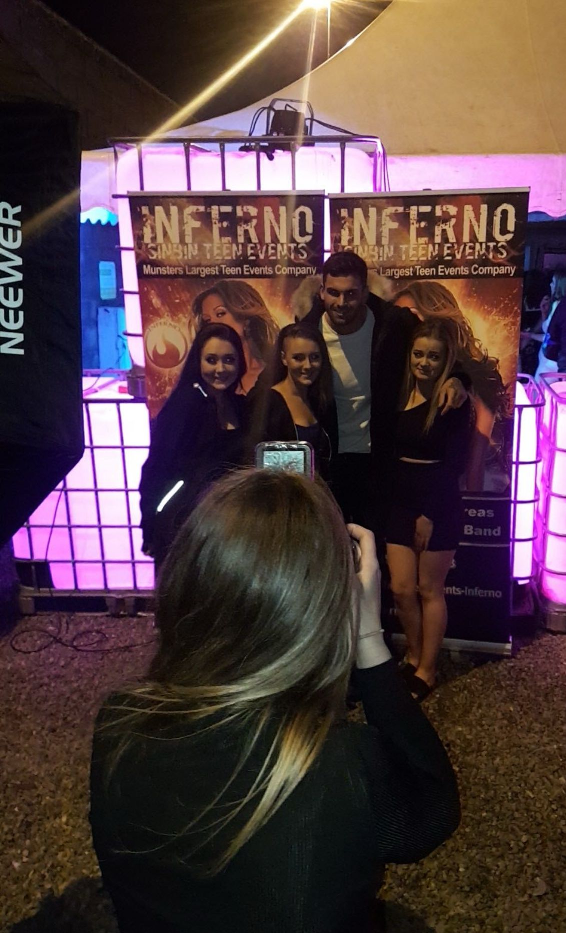 Group of teens posing for a photo at an Inferno teen events backdrop at a nighttime outdoor event.