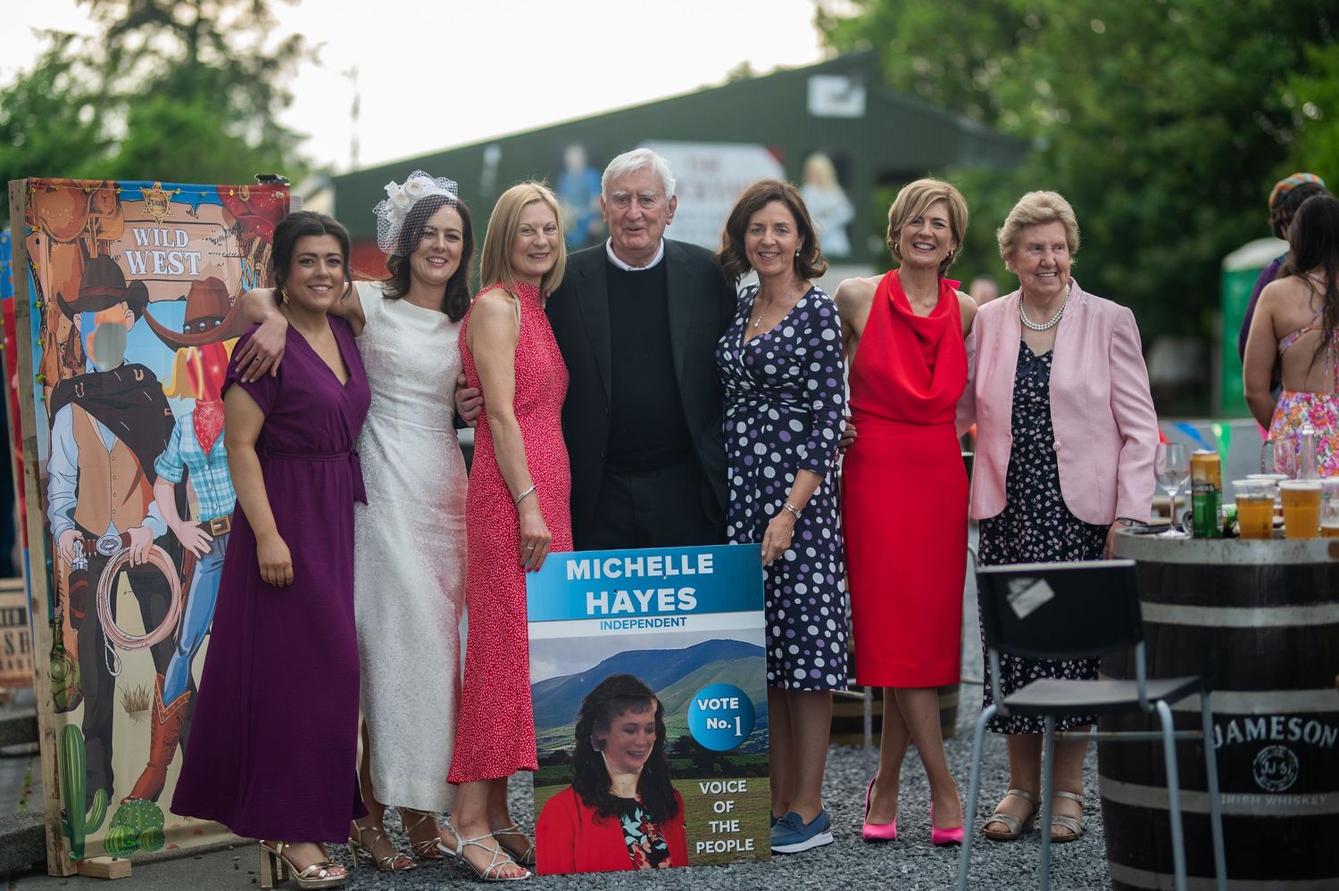 Group of elegantly dressed guests posing with a Michelle Hayes campaign sign.