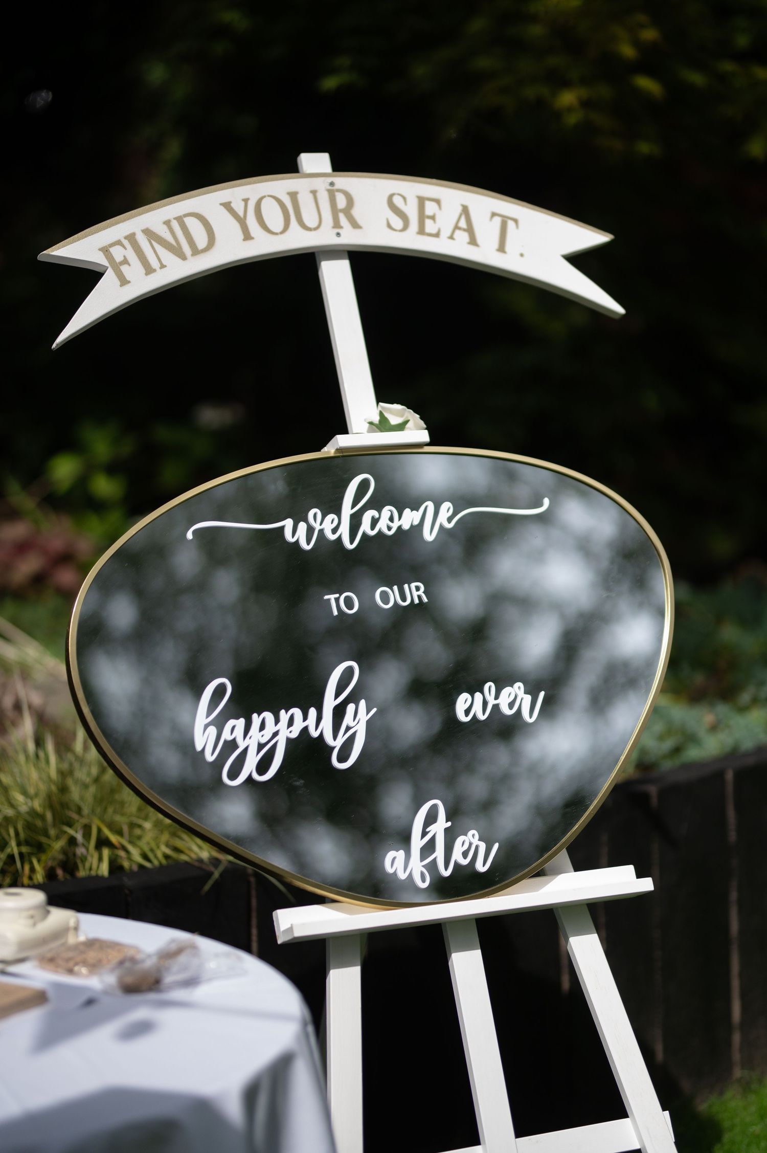 Wedding welcome sign on easel reading welcome to our happily ever after find your seat.
