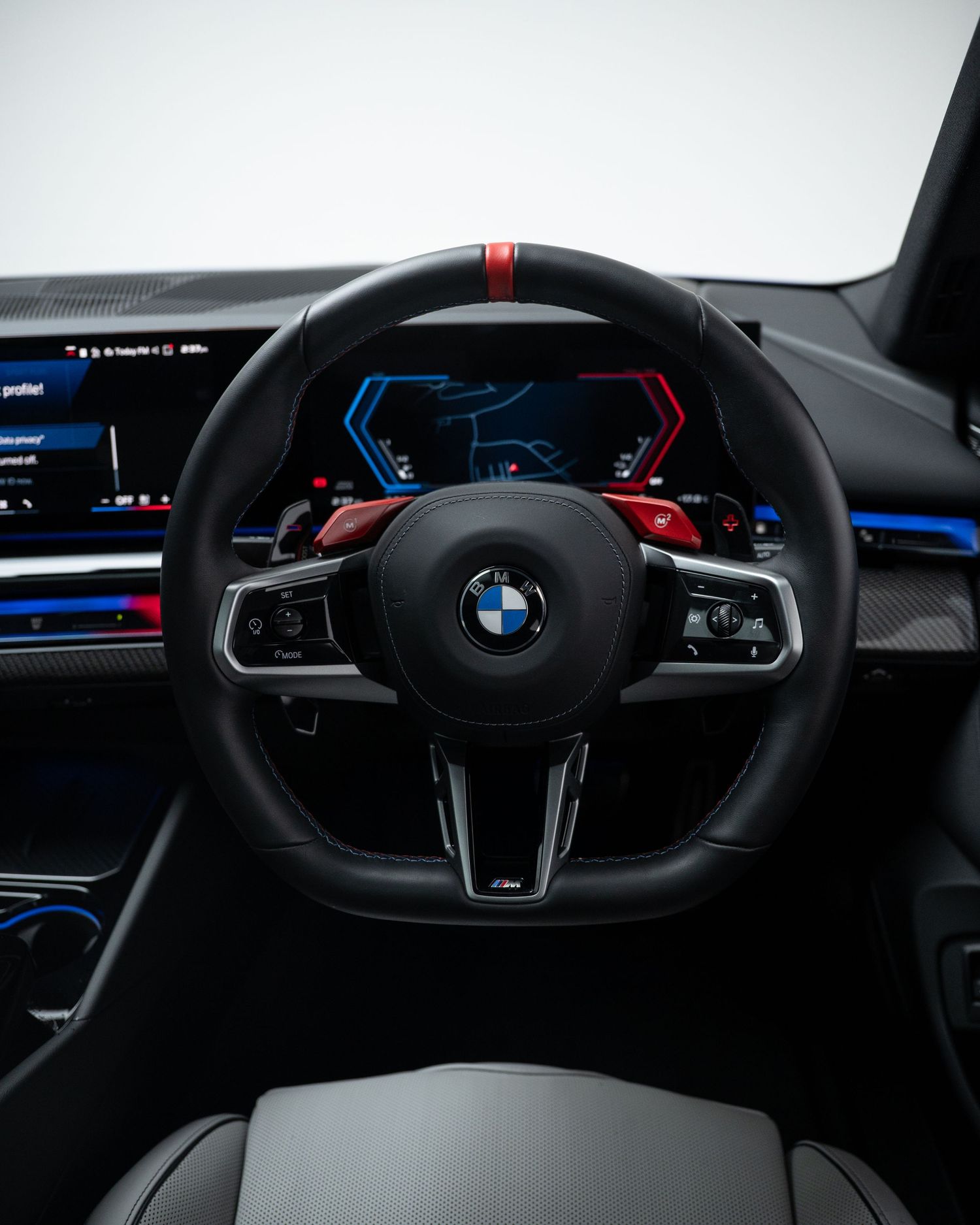 BMW M series steering wheel and digital dashboard display in a luxury sports car interior.