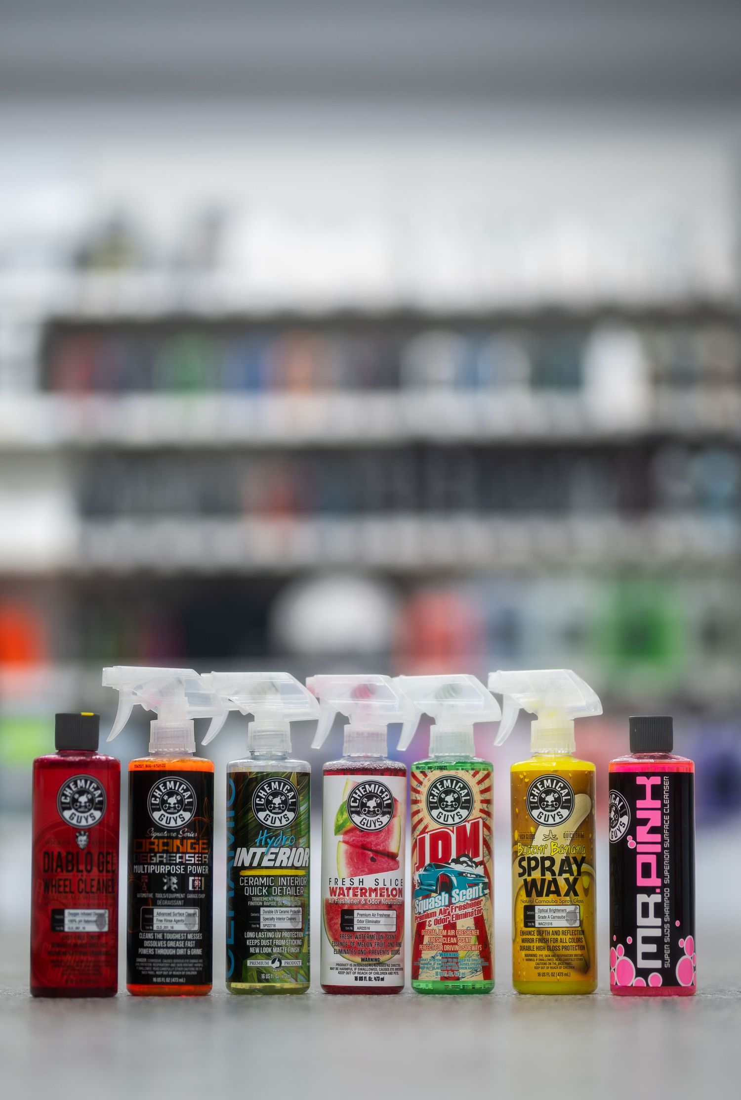 Seven Chemical Guys car care spray bottles lined up on a surface in a retail store setting.