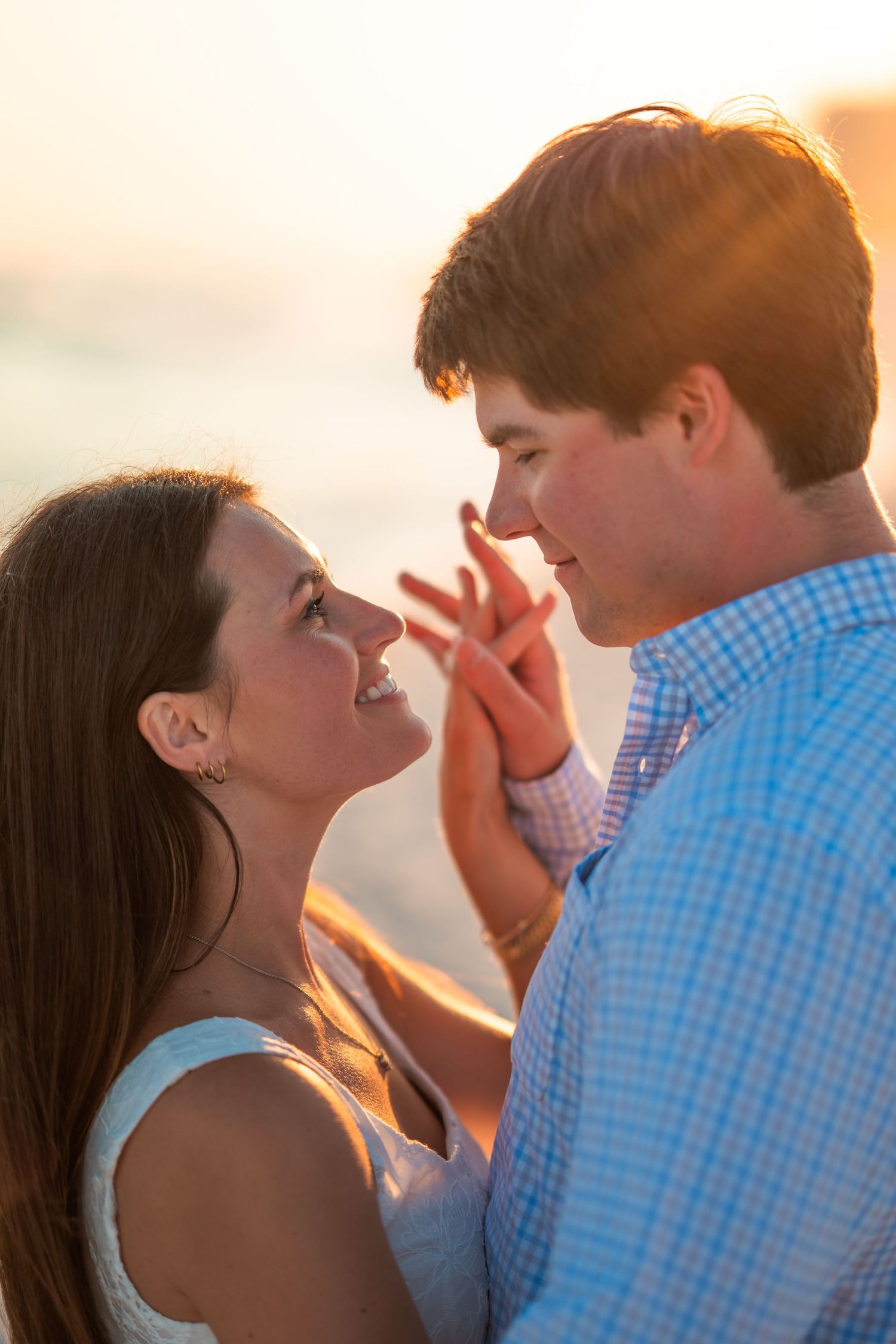 Tender moment shared between couple during beach sunset with golden lighting.