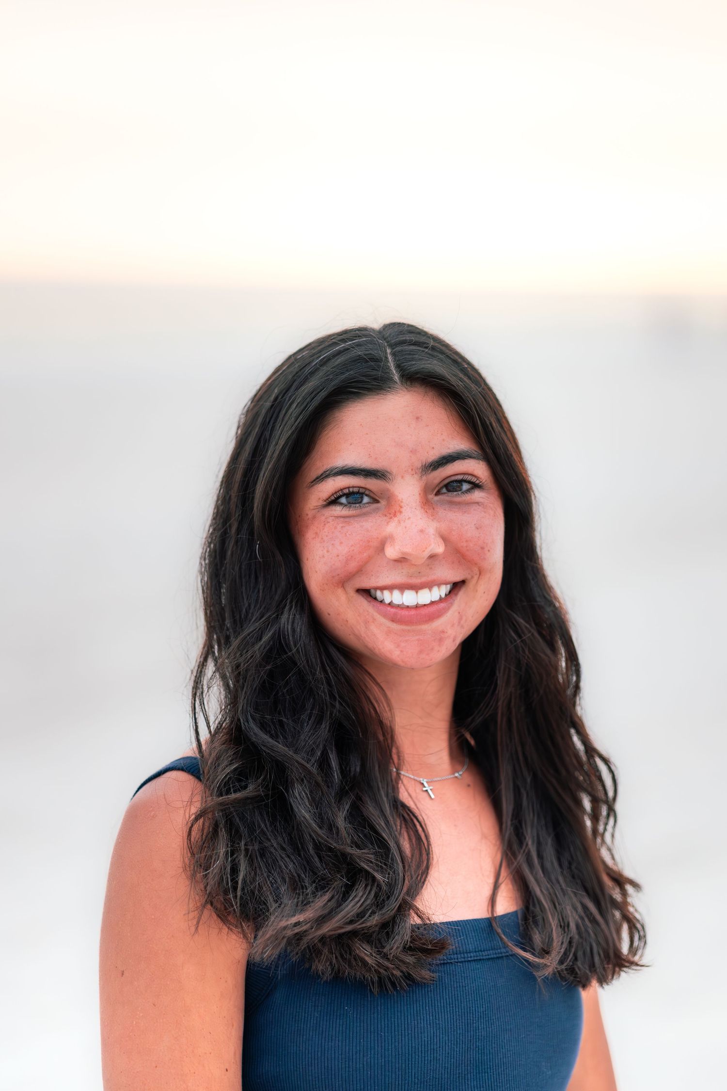 Portrait in navy blue top against bright neutral background.