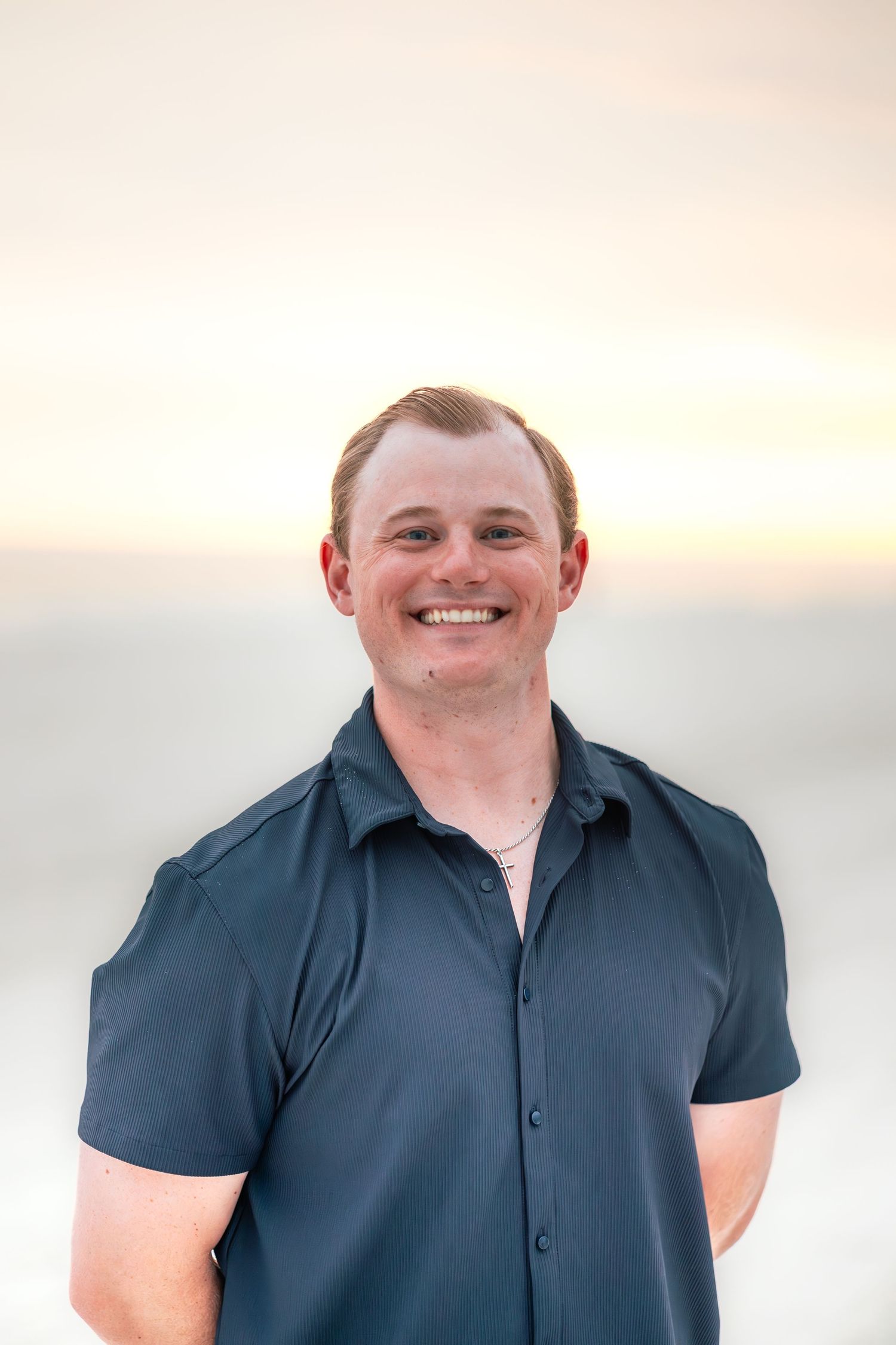 Portrait in navy blue shirt against sunset sky background.