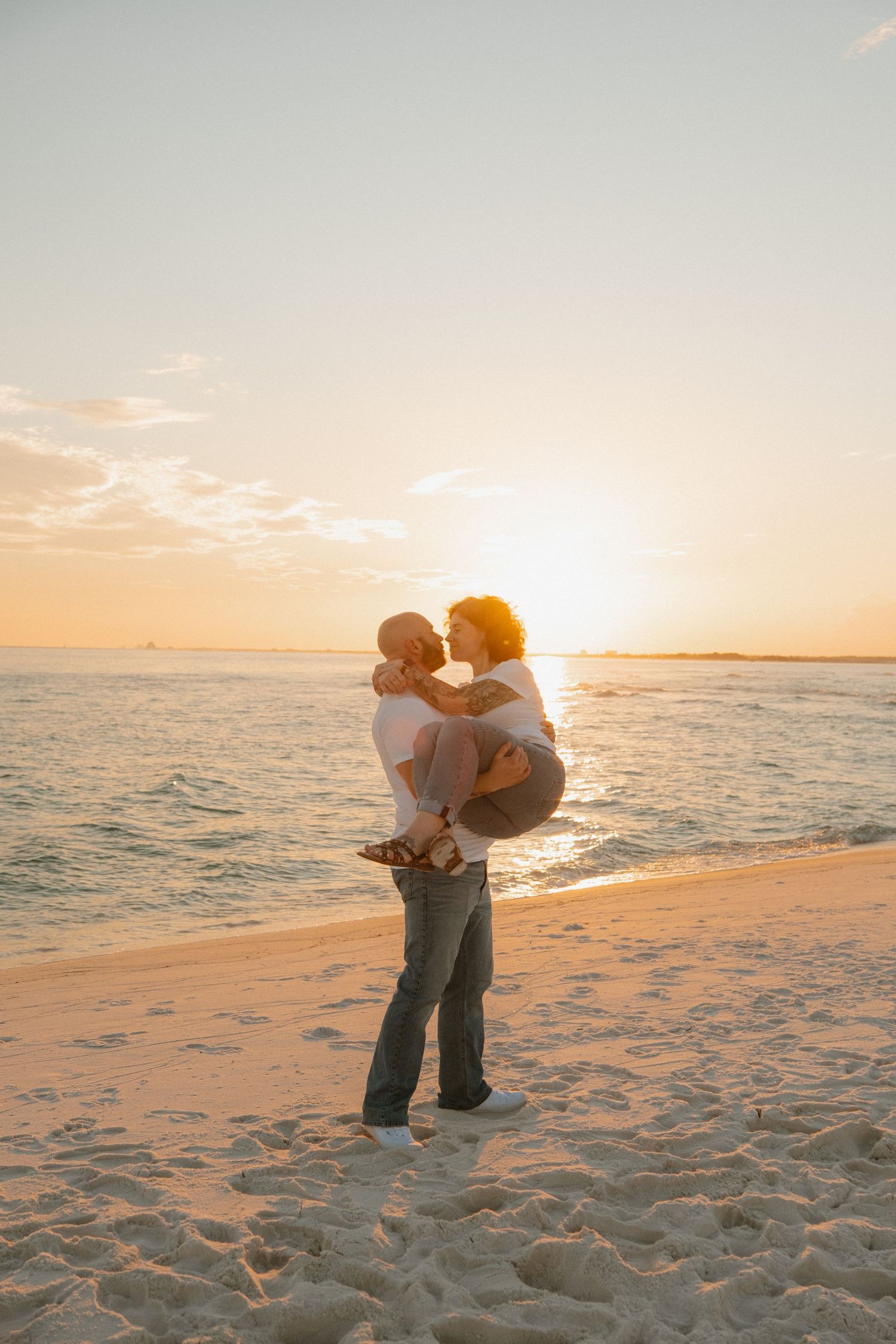 Two people sharing an embrace on a pristine white sandy beach at sunset.