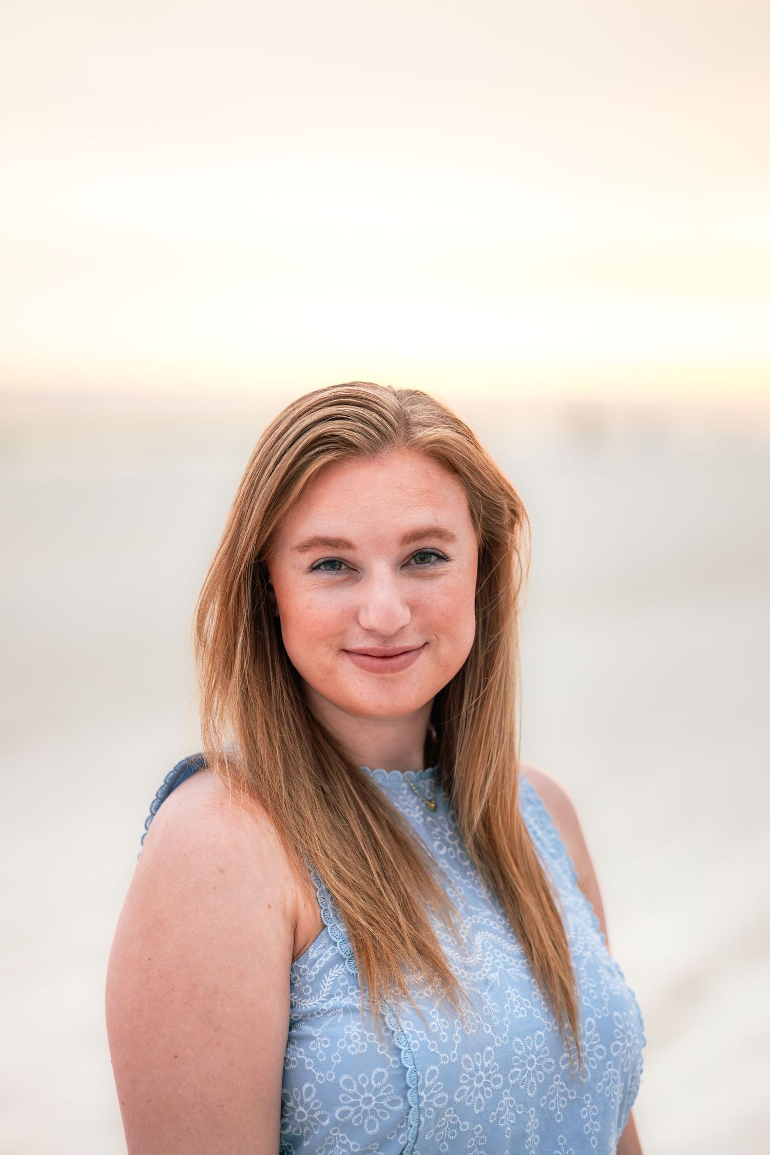Portrait in light blue lace top against soft sunset lighting.