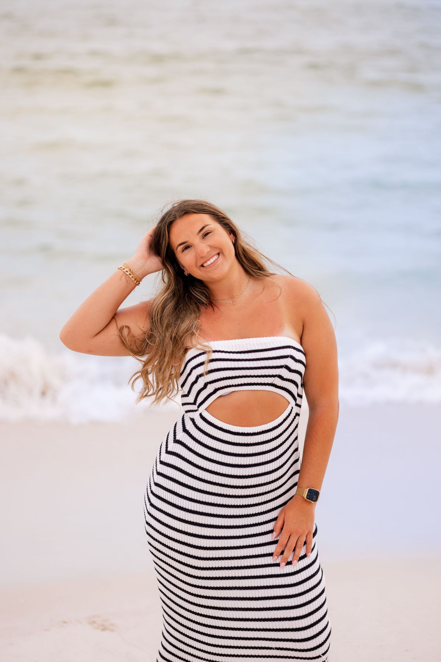 A series of joyful poses in a black and white striped dress on a sunny beach.