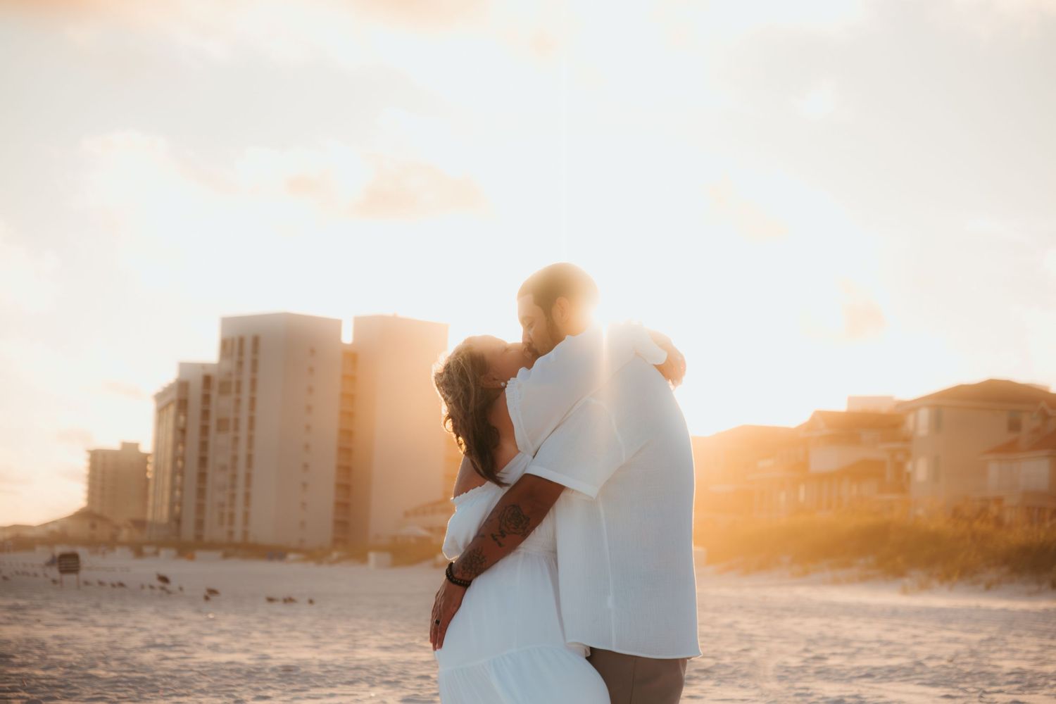 A romantic sunset beach scene with two silhouettes walking together on the shoreline.