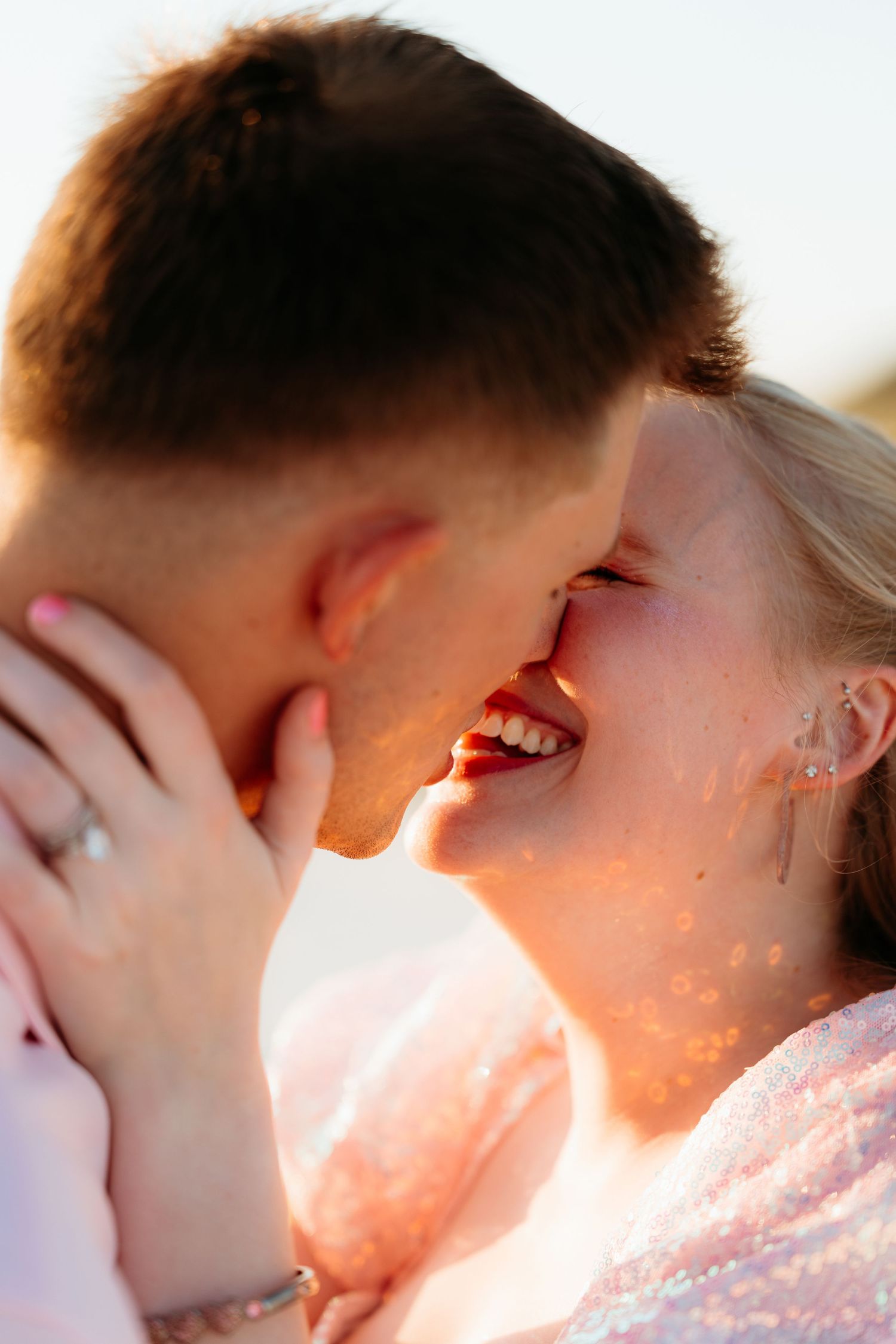 Silhouetted couple sharing an intimate kiss at sunset with warm golden light glowing between them.