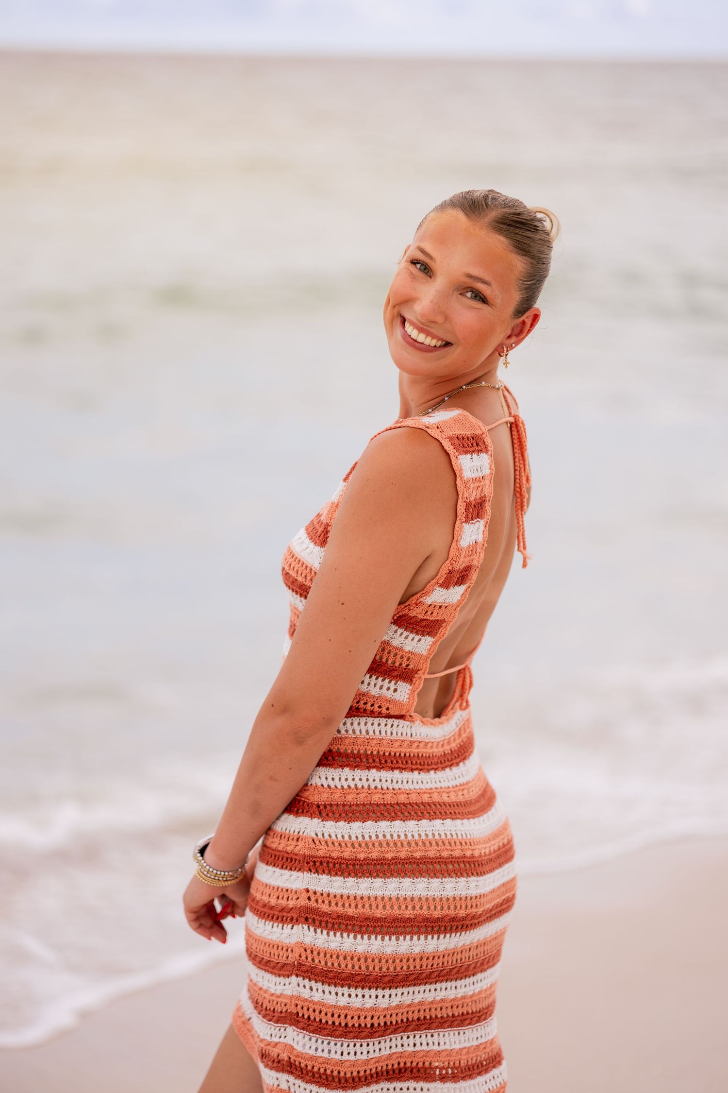 Red and white striped dress on beach with ocean waves in background.