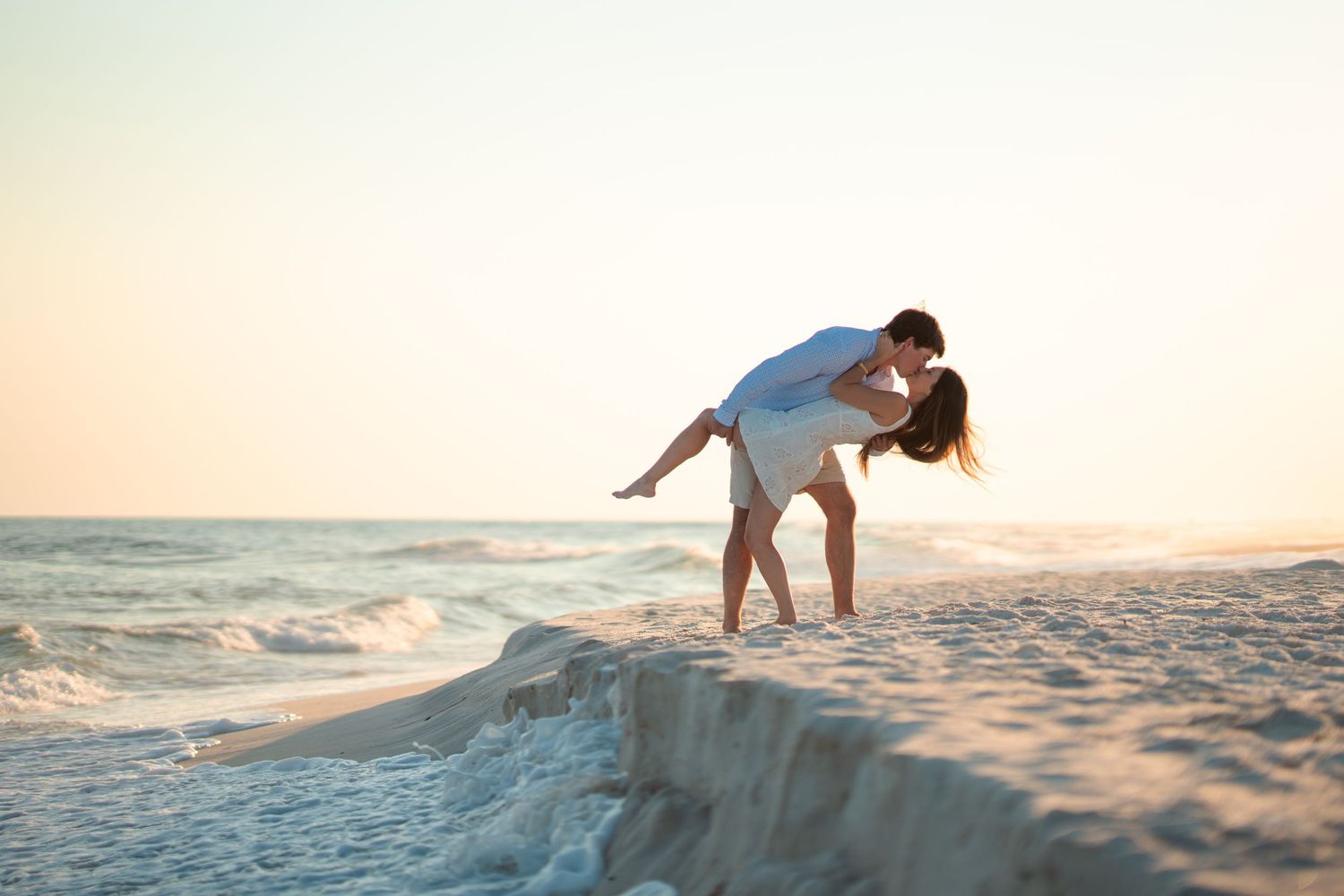 Couple enjoying a sunset moment together in the sandy beach dunes.