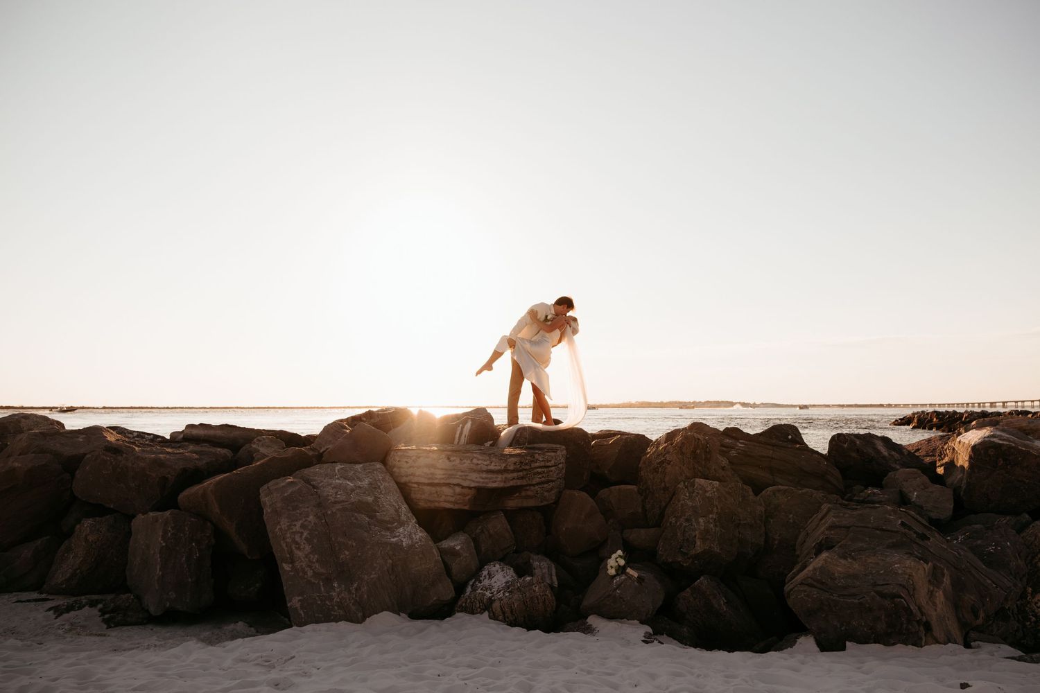 Beautiful sunset over rocky coastline with ocean waves crashing against the shore.