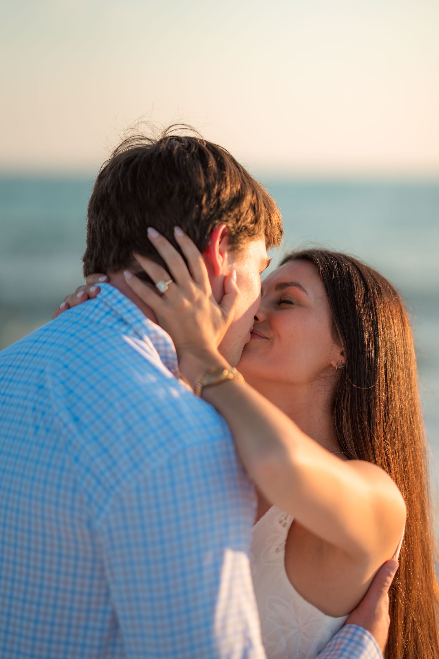 Intimate beach moment captured during golden hour with ocean backdrop.