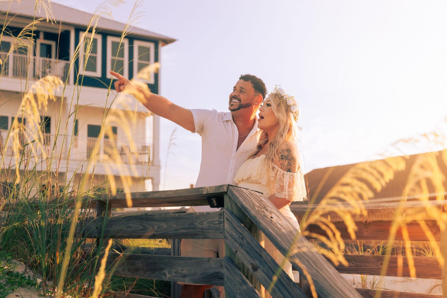 A couple embraces on a seaside pier during golden hour.