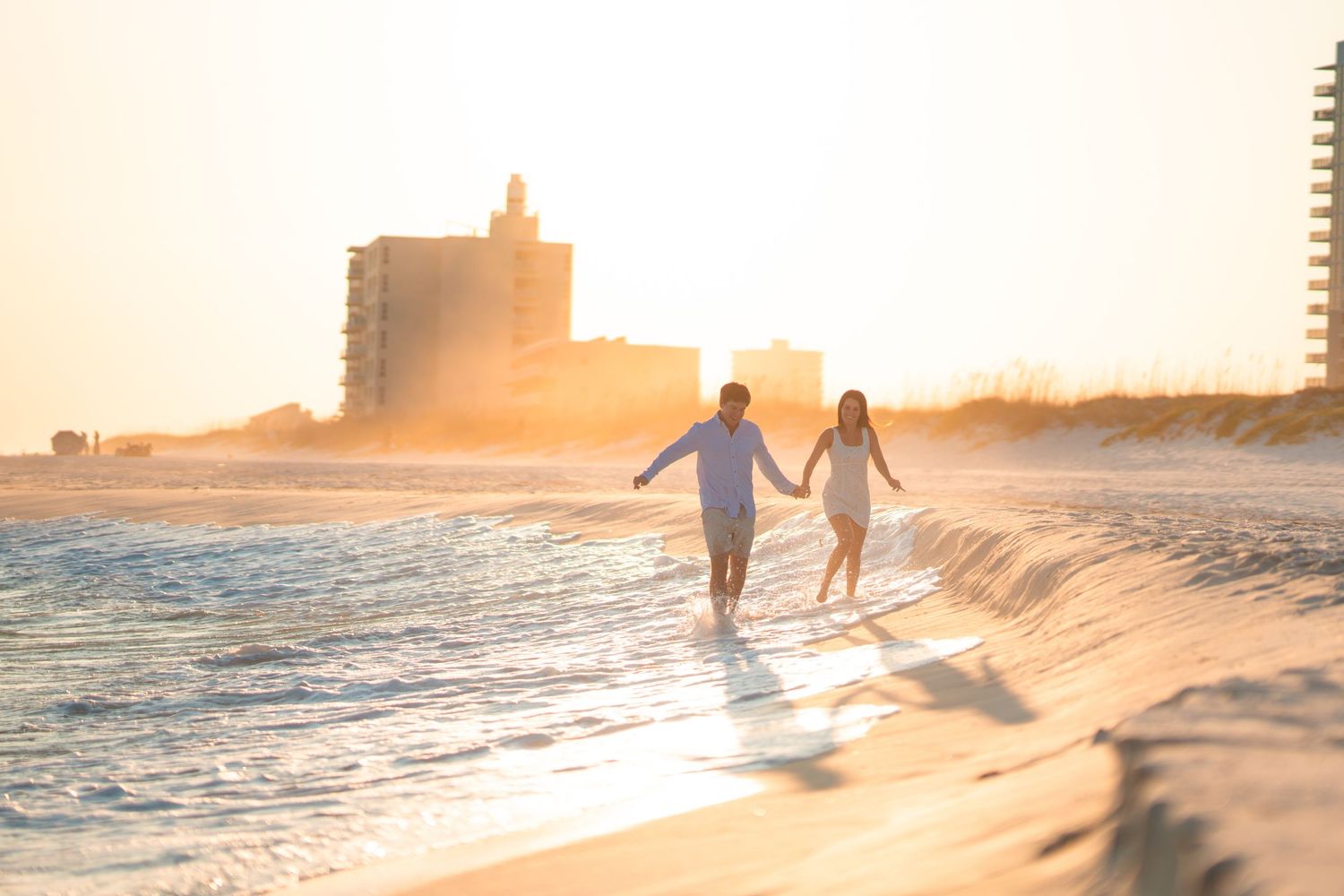 Silhouetted figures walking along beach shoreline during golden sunset.
