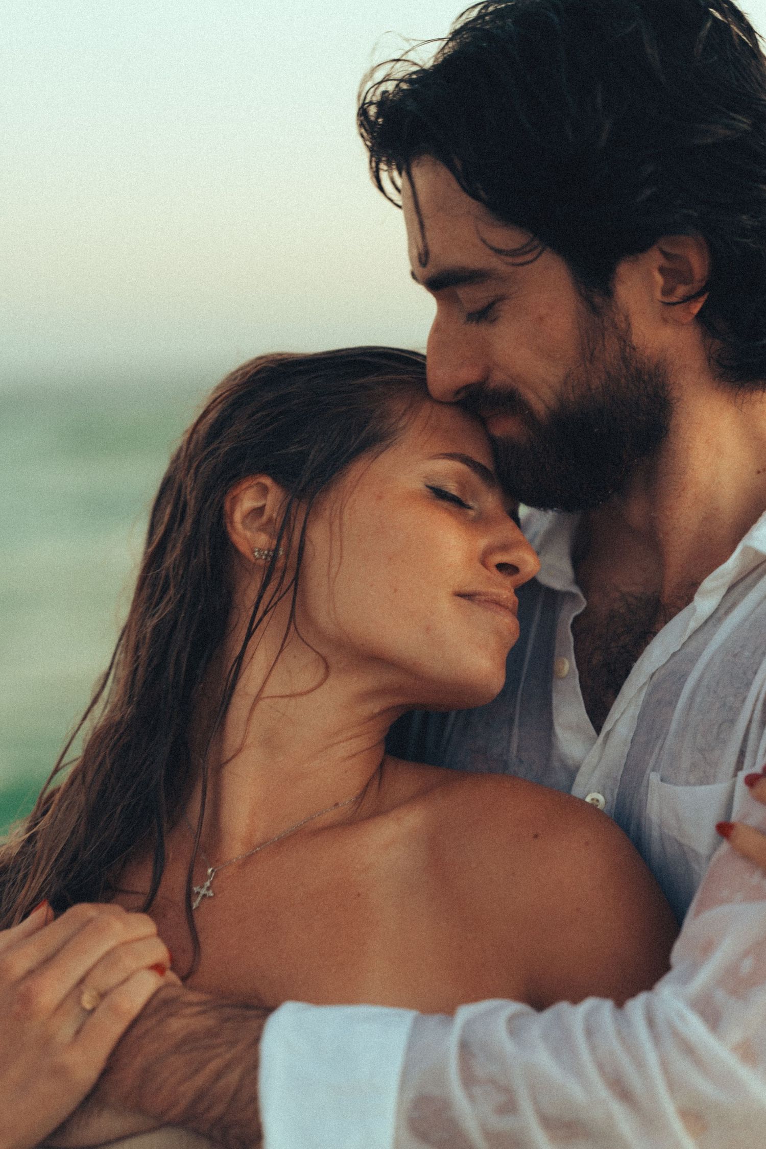A romantic couple shares intimate moments by the ocean in a series of tender embraces.