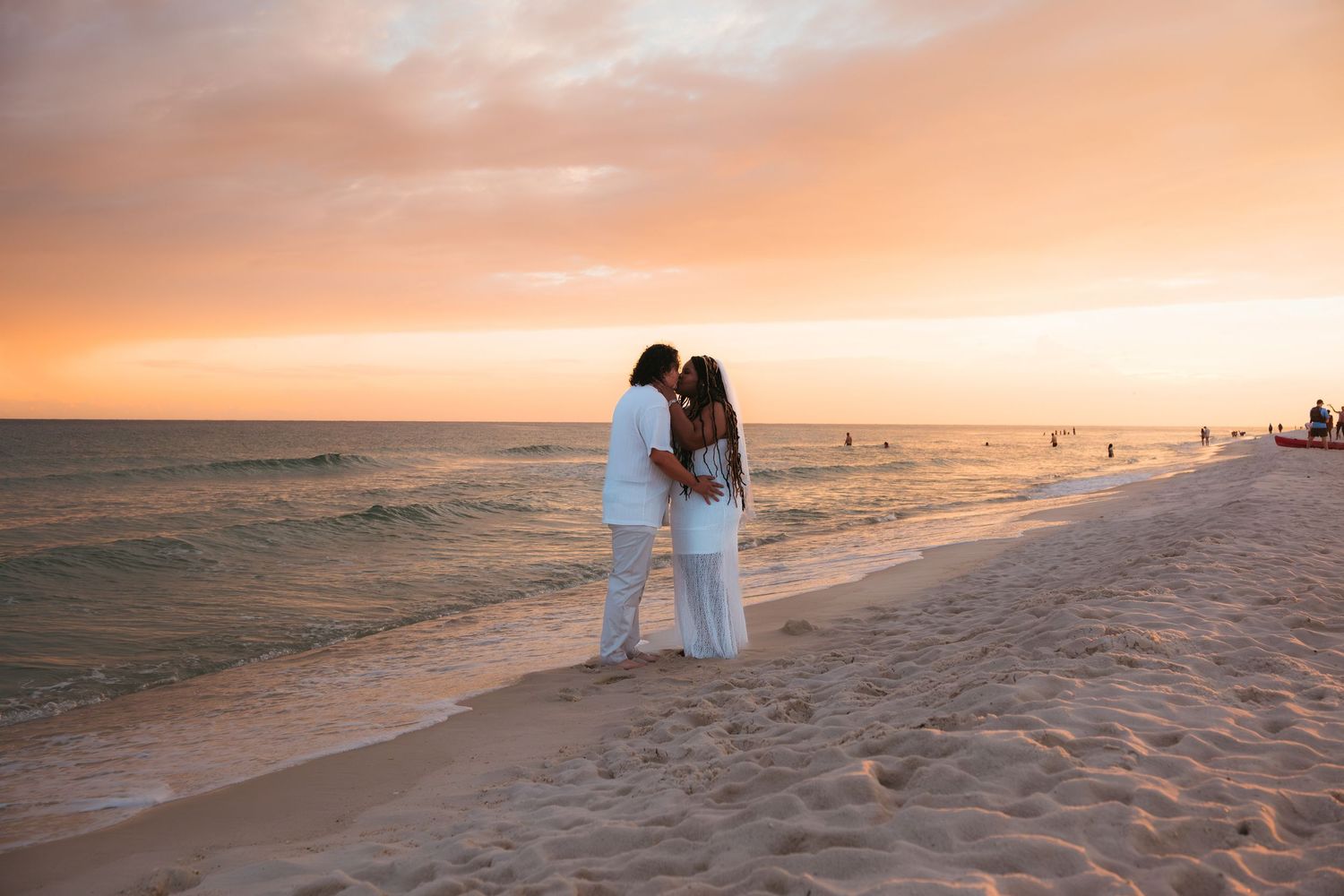 A romantic beach walk at sunset with dramatic orange and pink sky reflecting on the ocean water.