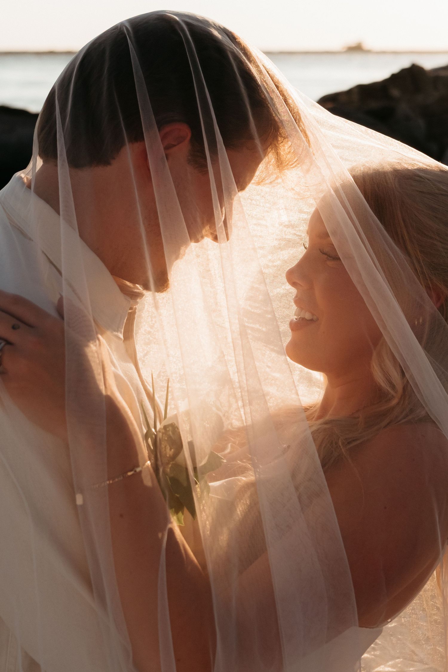 Ethereal silhouette of a couple under a wedding veil with sunlight streaming through.