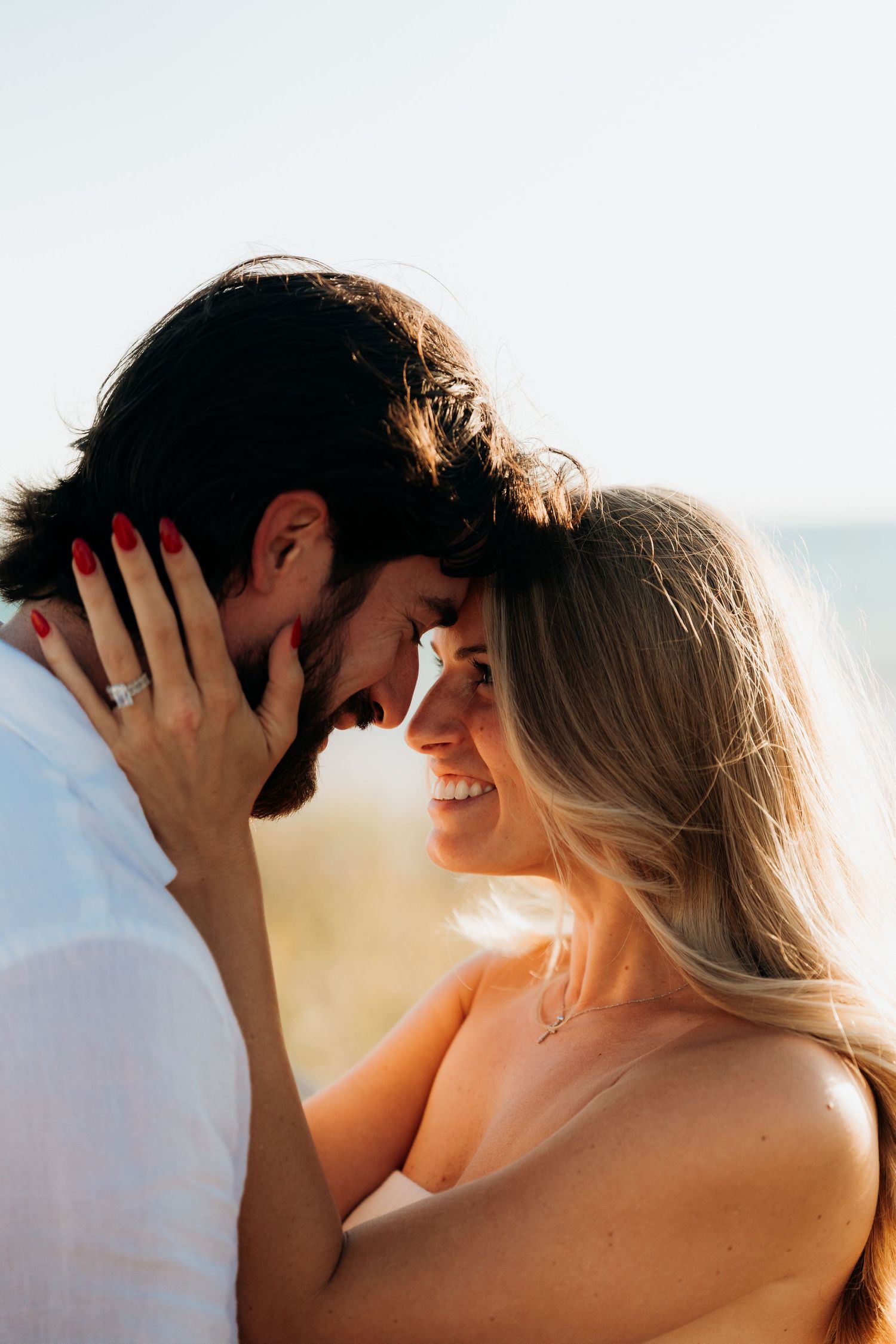 A romantic couple shares an intimate moment at sunset with warm golden light illuminating their silhouettes.