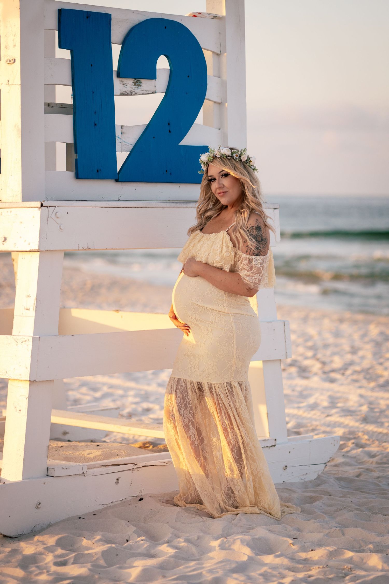 A beach photoshoot featuring a cream-colored dress among white pillars on sandy shores.