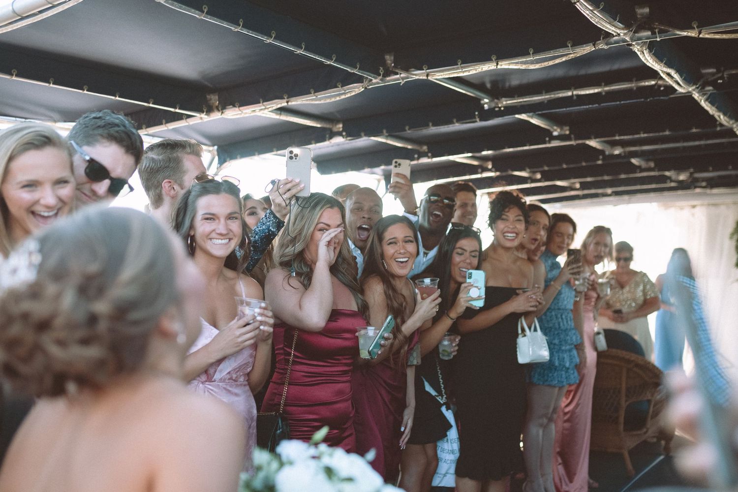 Excited wedding guests celebrating together on a boat during a wedding reception.