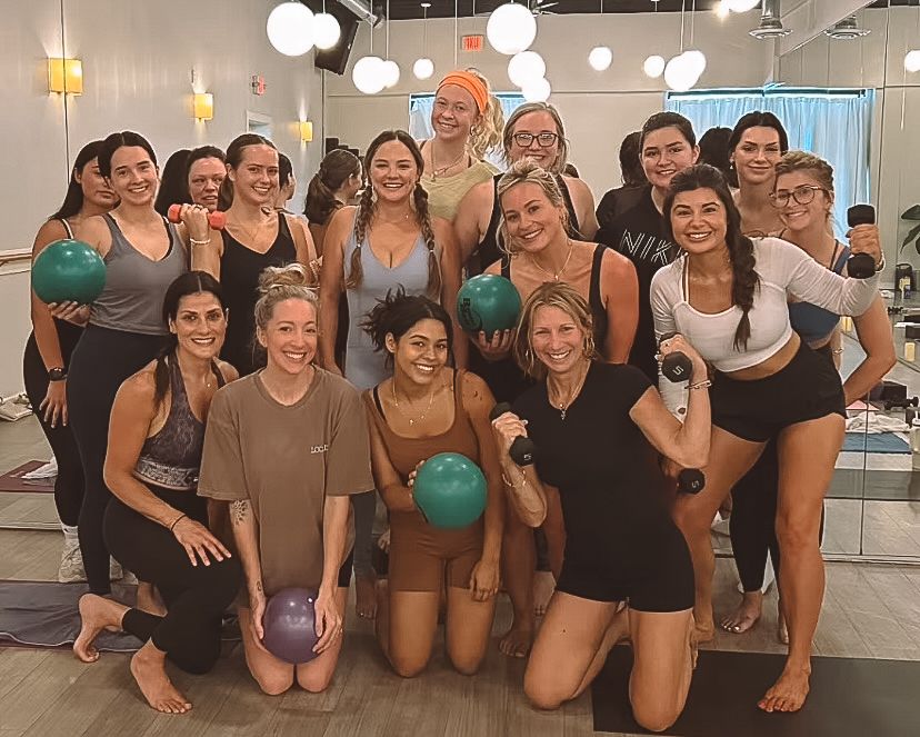 Group of women posing with exercise balls in a fitness studio.