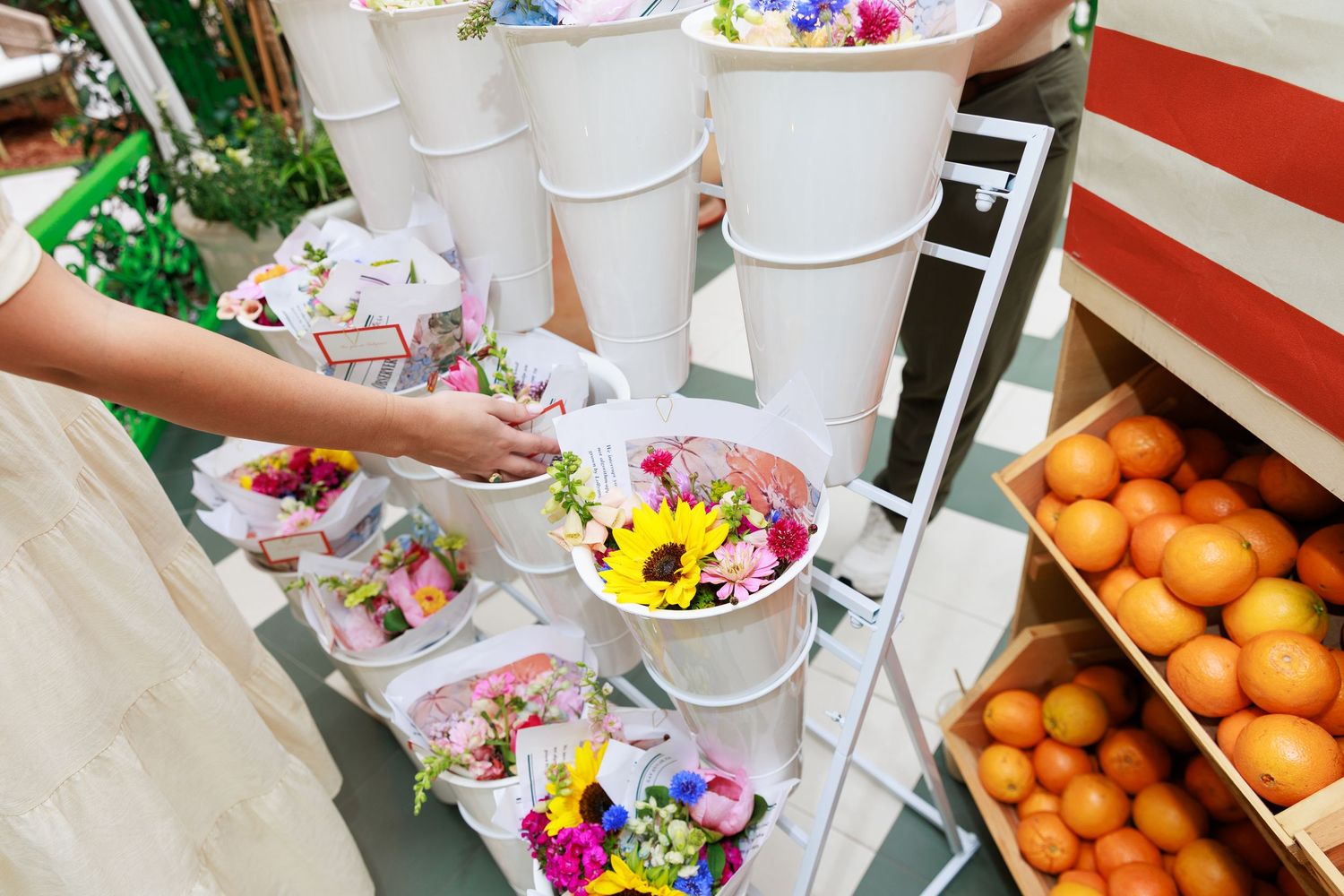 Colorful fresh flower bouquets displayed in white buckets at a vibrant outdoor flower market stand.