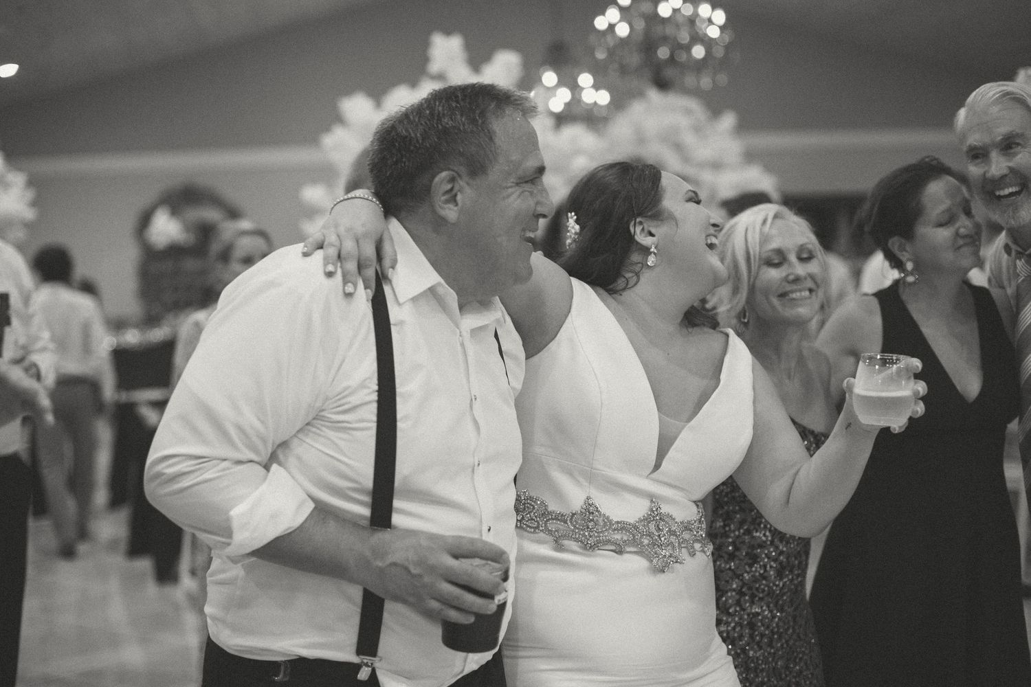 Joyful bride and groom laughing together at their wedding reception in black and white photo.