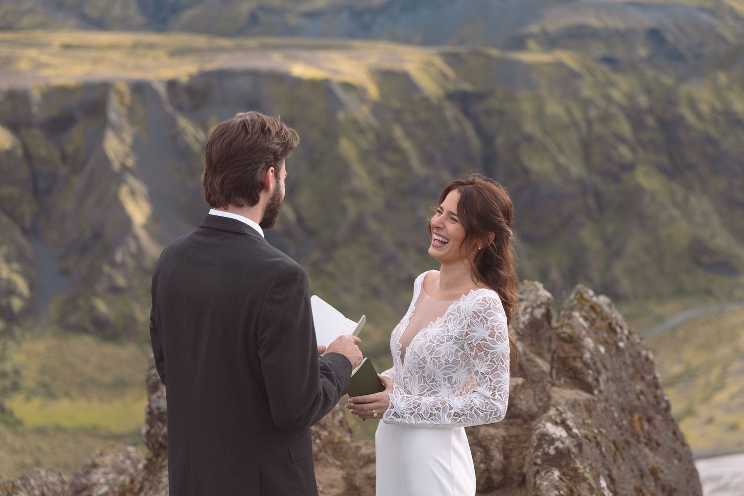 Bride smiles broadly at groom during heartfelt vow exchange at scenic Iceland mountain elopement.