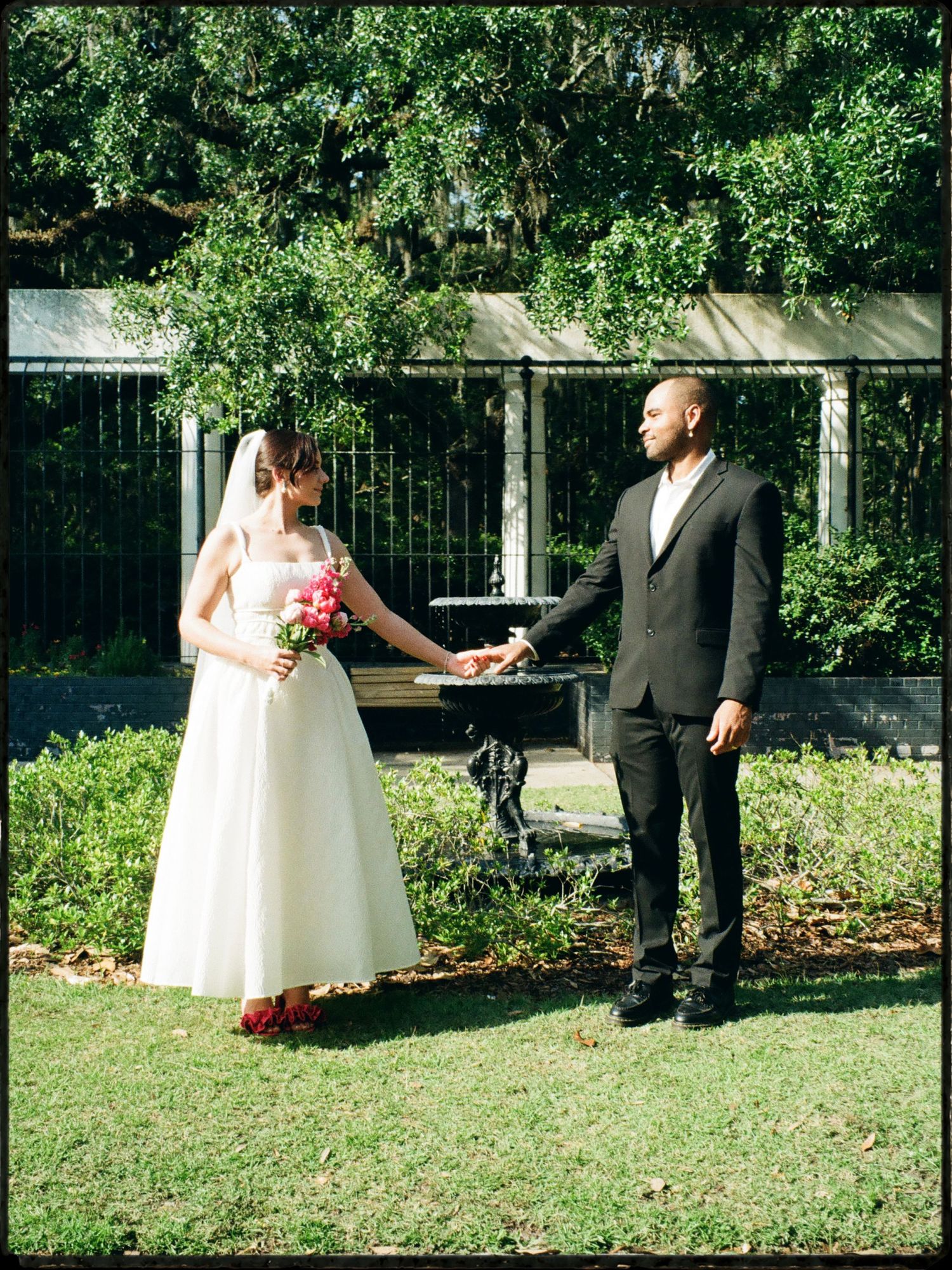 Interracial bride and groom sharing a first look moment in a lush garden during their wedding day.