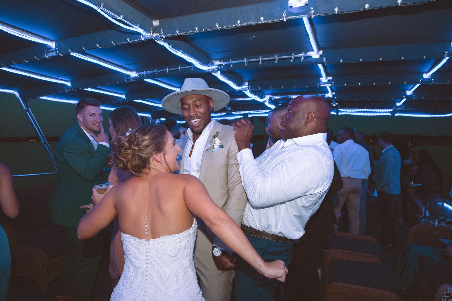 Bride and groom celebrating with a guest on the dance floor at their wedding reception.