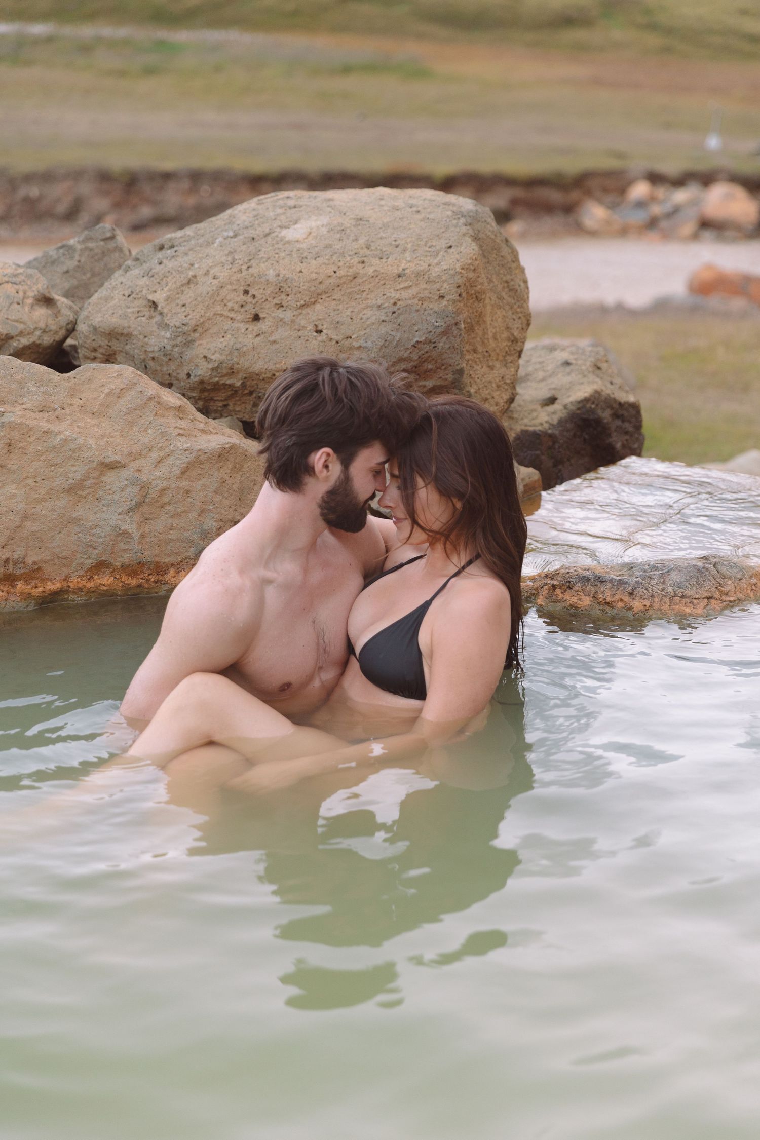 Romantic couple embracing and kissing in a natural geothermal hot spring pool in Iceland.