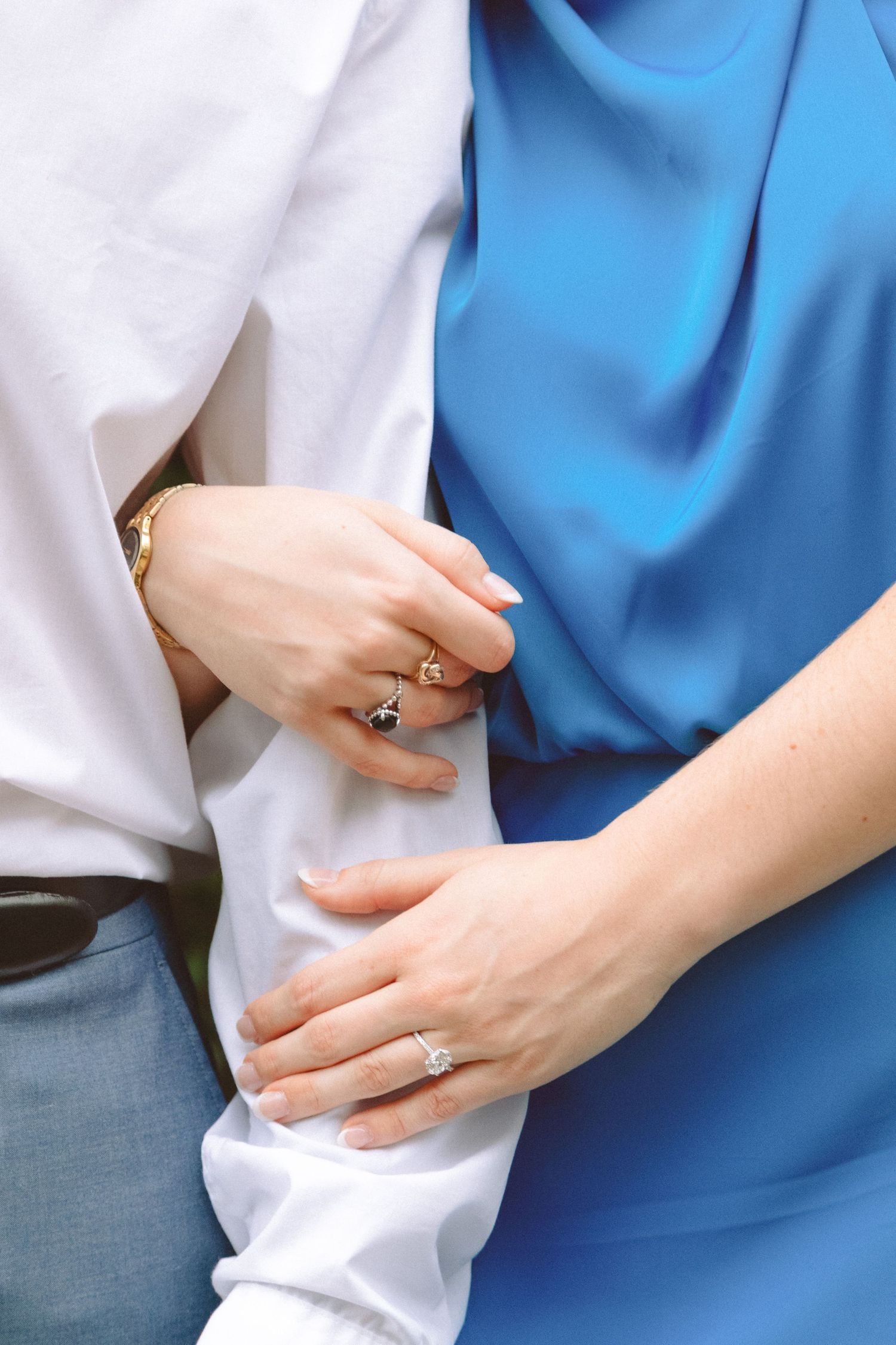 Close-up of couple embracing, woman wearing diamond engagement ring and gold ring on her hand.