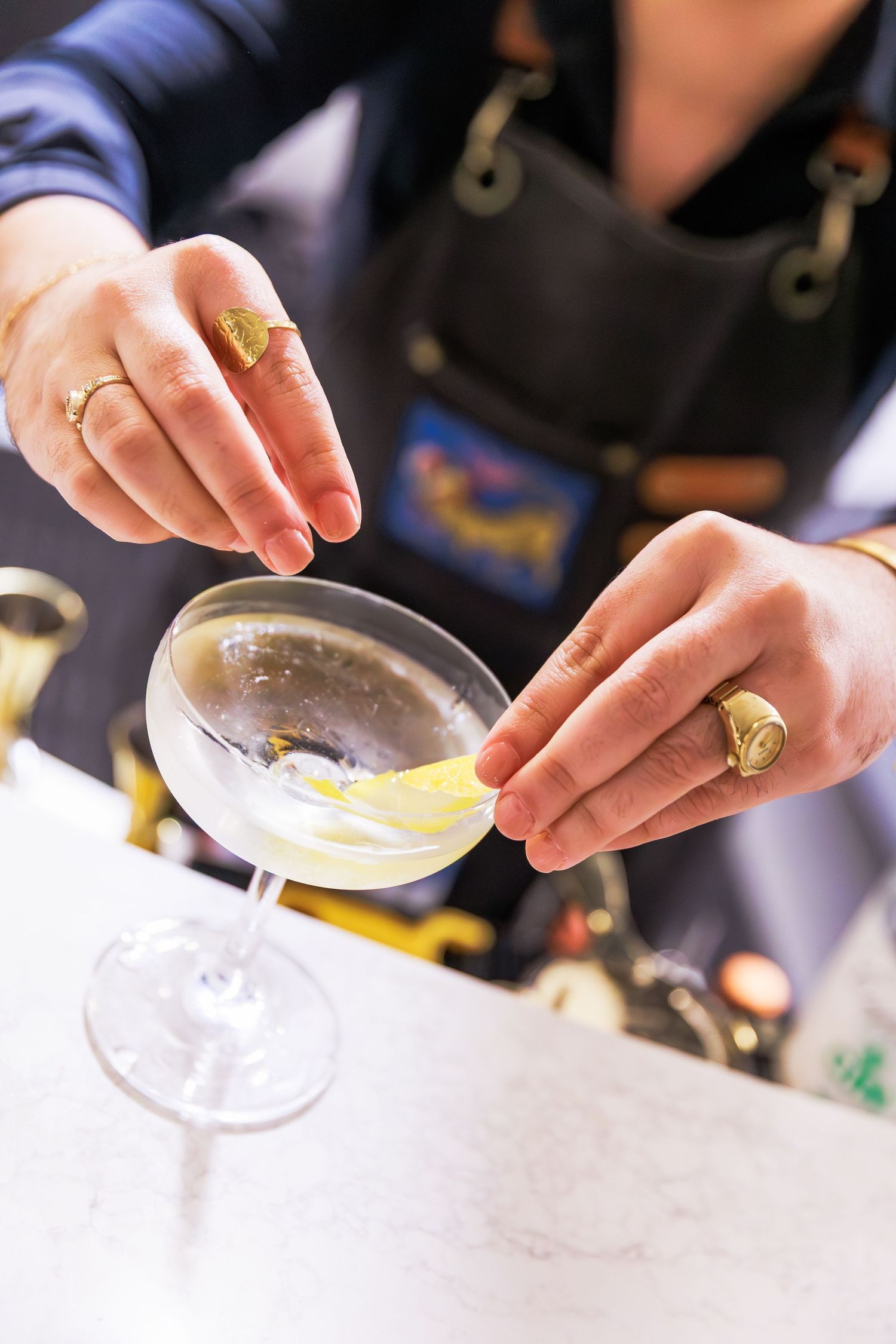 Bartender garnishing a classic martini cocktail with a lemon twist in an elegant coupe glass.
