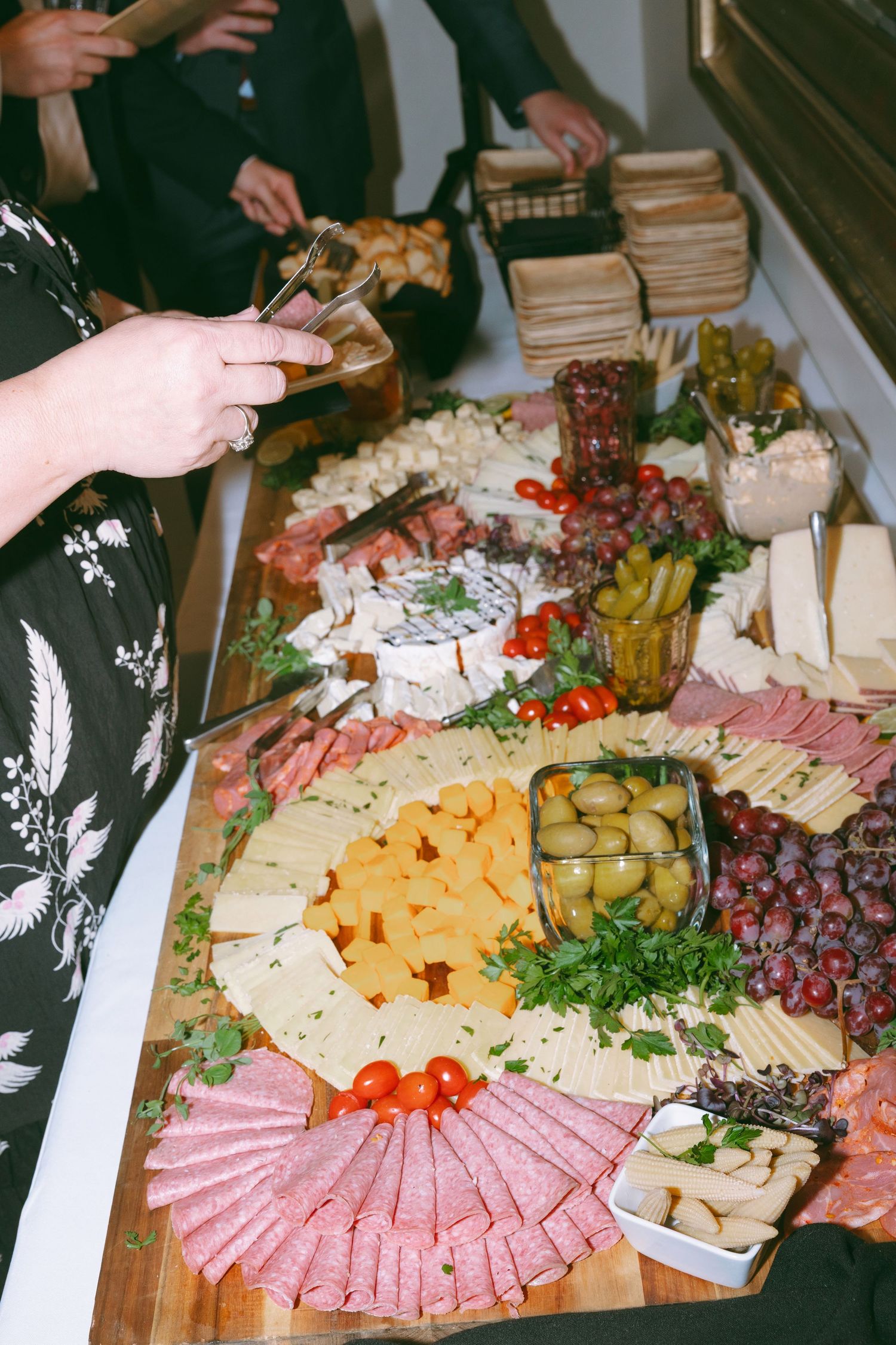 Elegant charcuterie board with assorted cheeses, salami, olives, grapes, and crackers at a catered event.
