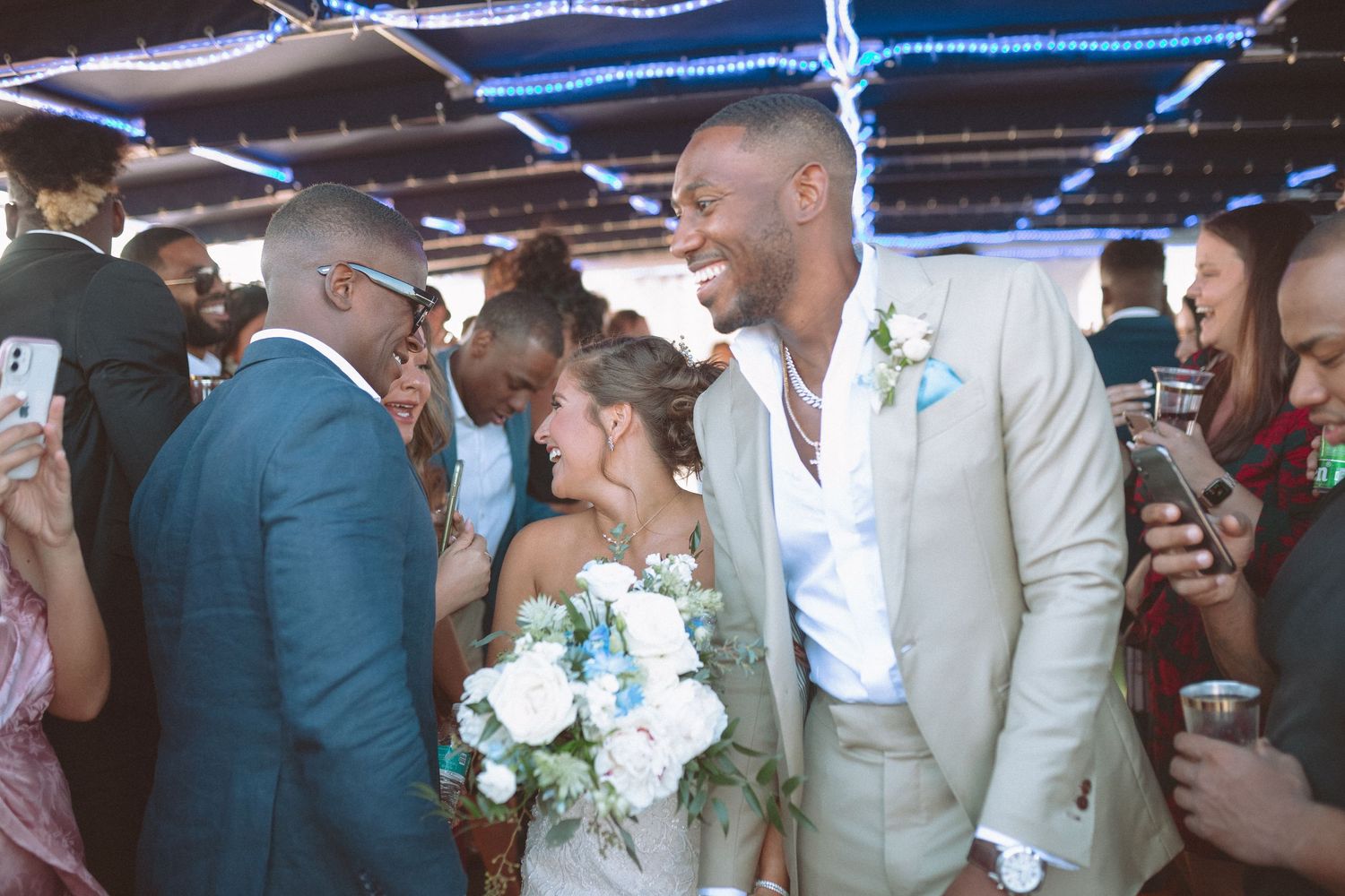 Newlyweds greeting smiling guests warmly after their wedding ceremony indoors.