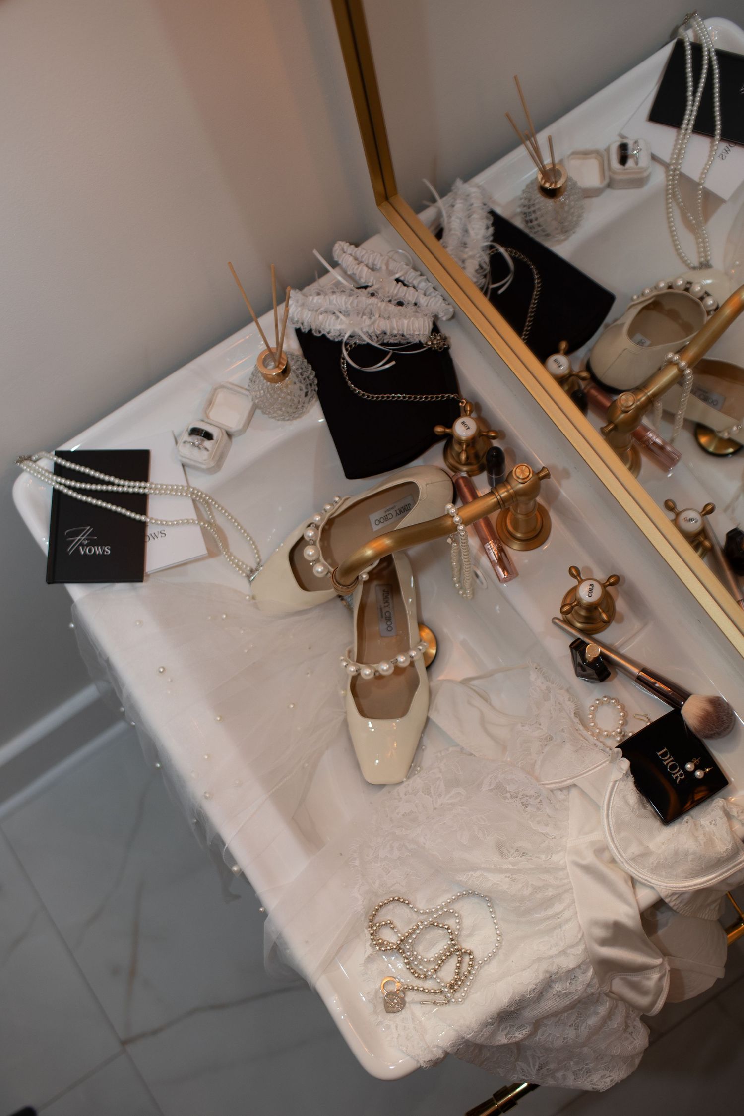 Bridal flat shoes adorned with pearls on white table with makeup, jewelry and accessories.