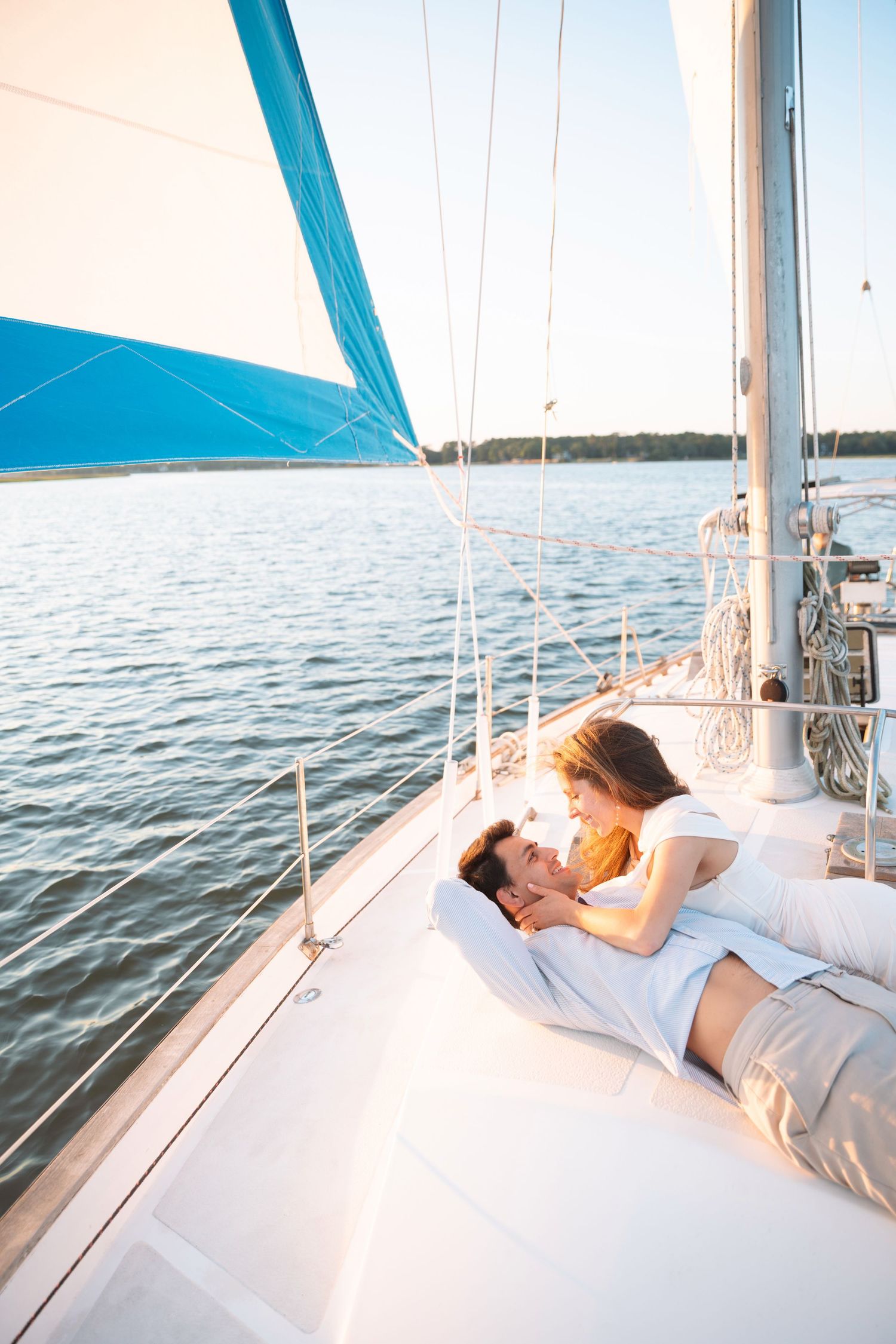 Romantic couple relaxing together on the deck of a white sailboat on calm water.