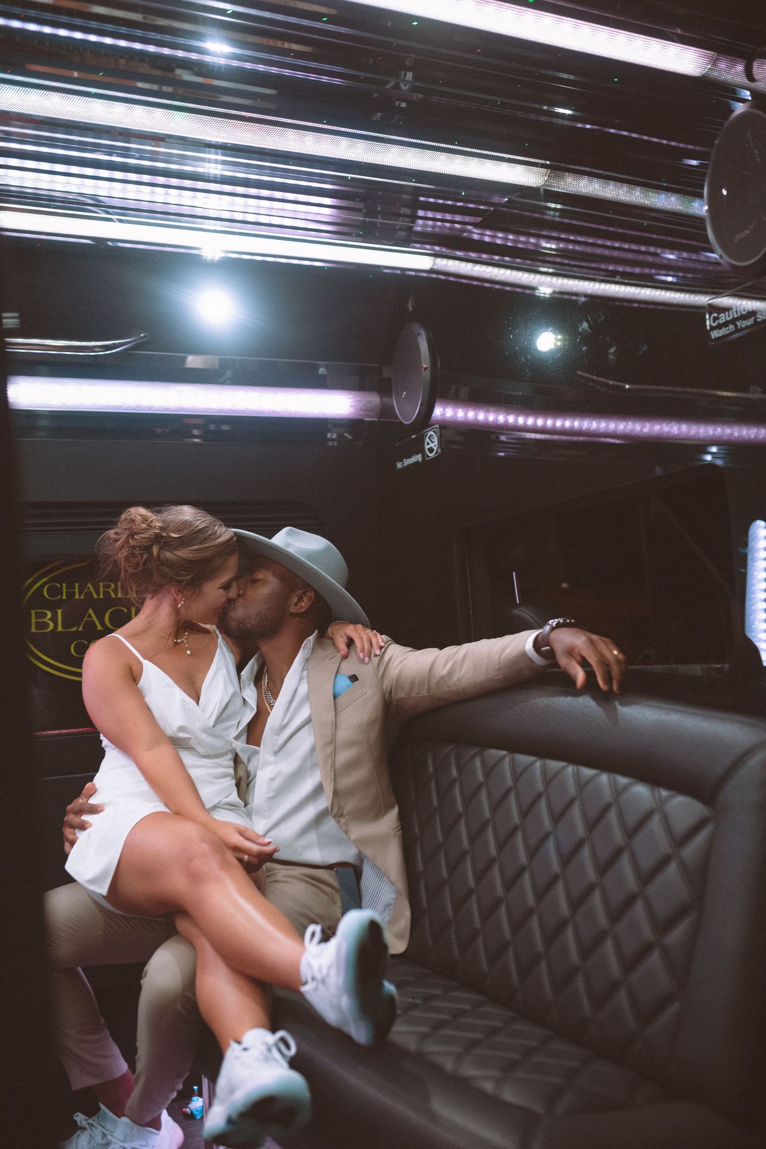 Newlyweds share a romantic kiss inside a decorated party bus after their wedding celebration.