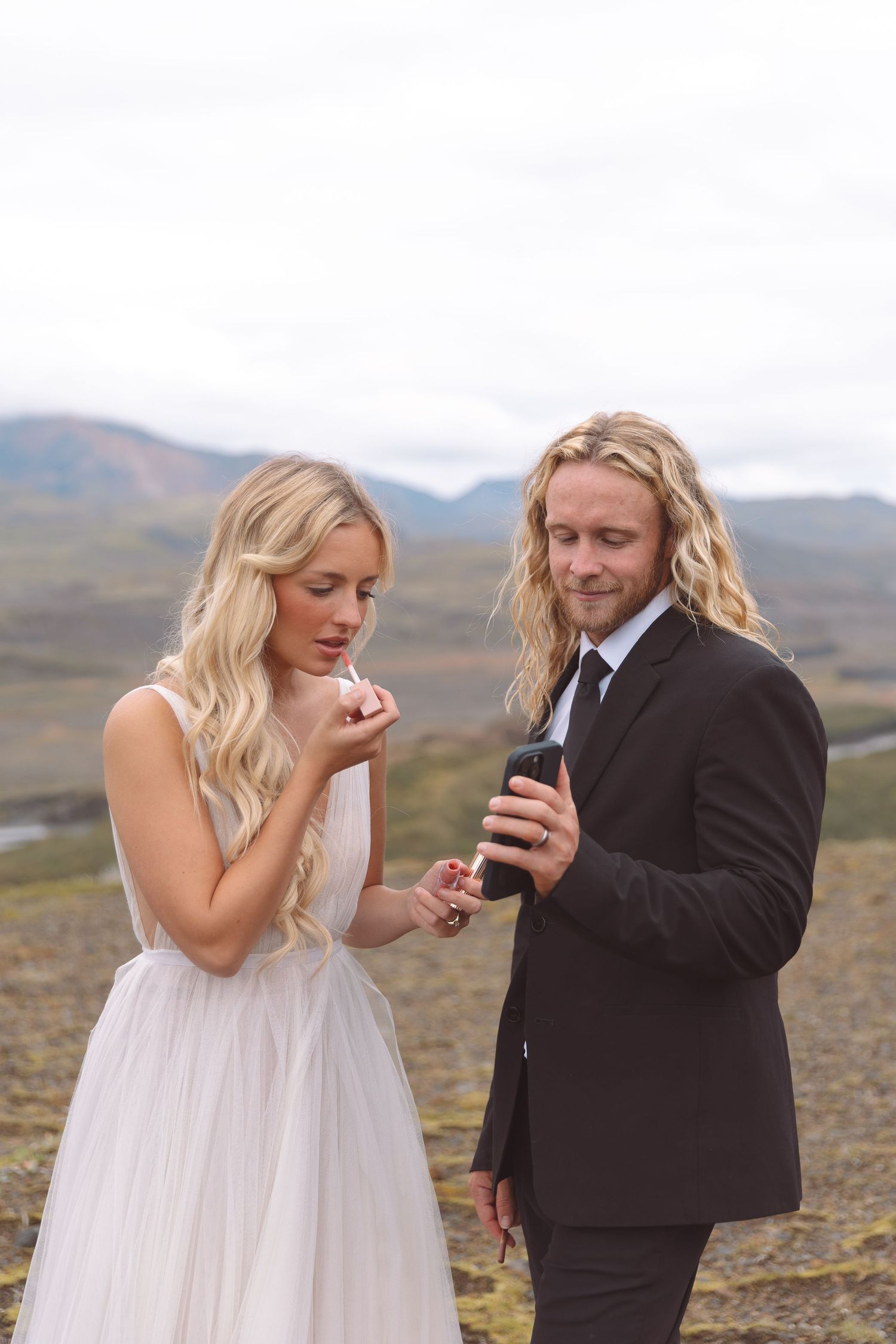 Bride and groom exchanging rings outdoors with scenic mountain landscape backdrop on their wedding day.