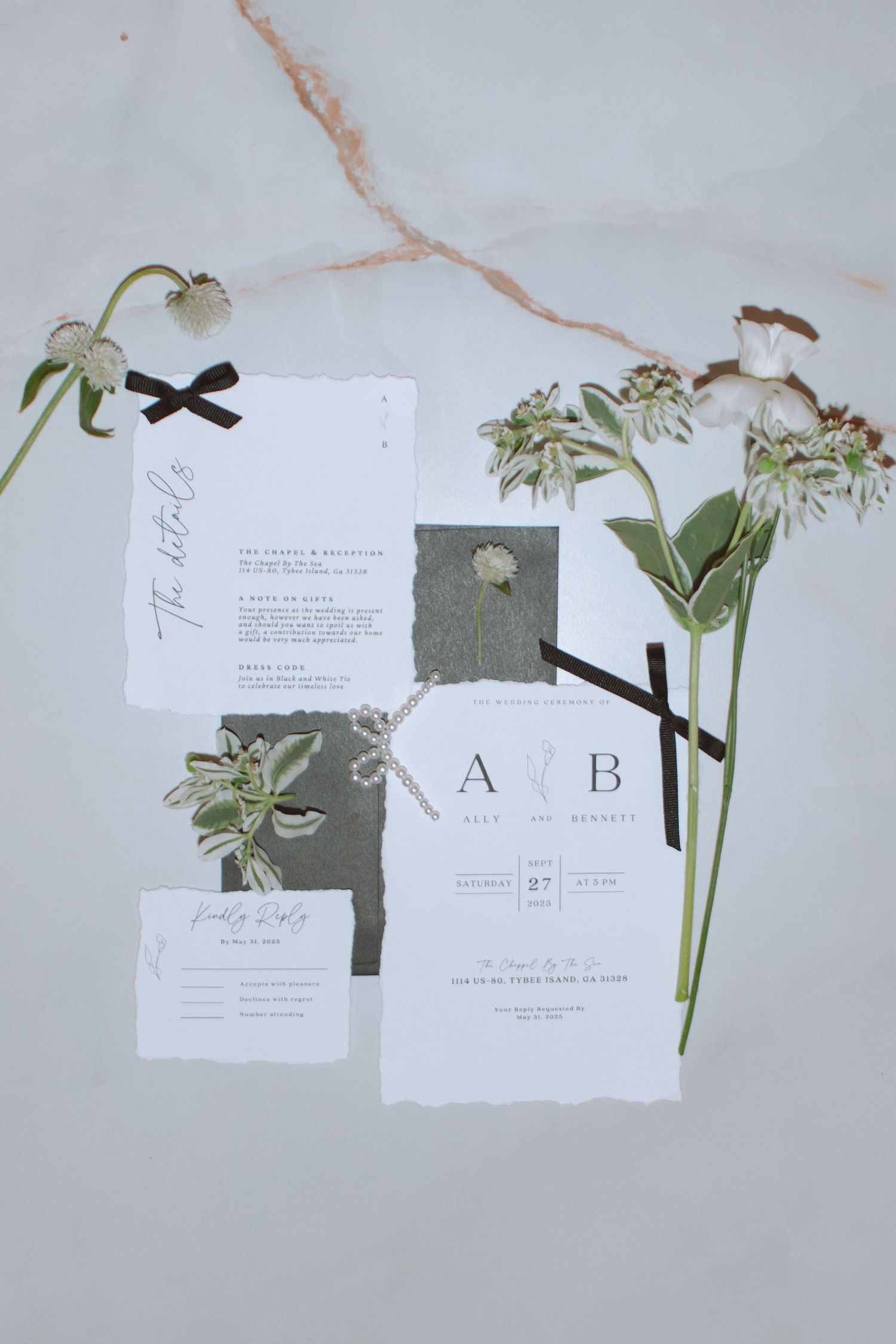 Minimalist wedding stationery suite with botanical pressed flowers, black velvet ribbon on marble background.