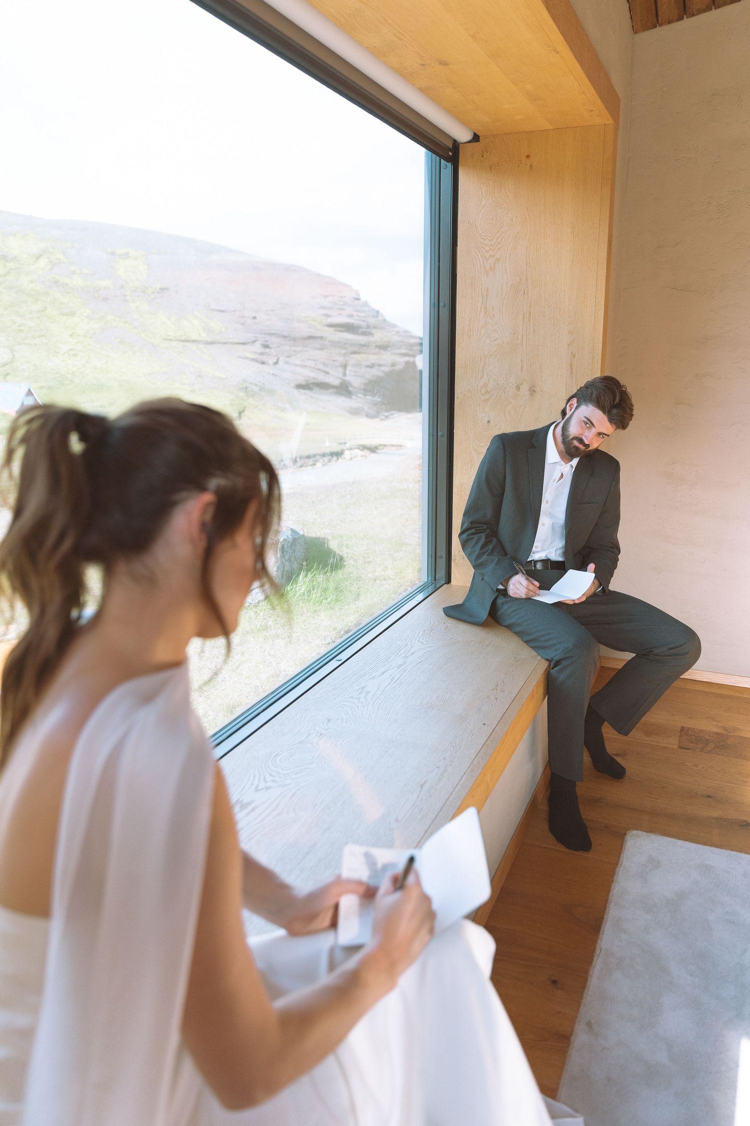 Bride and groom reading their wedding vows separately inside a modern rustic cabin.