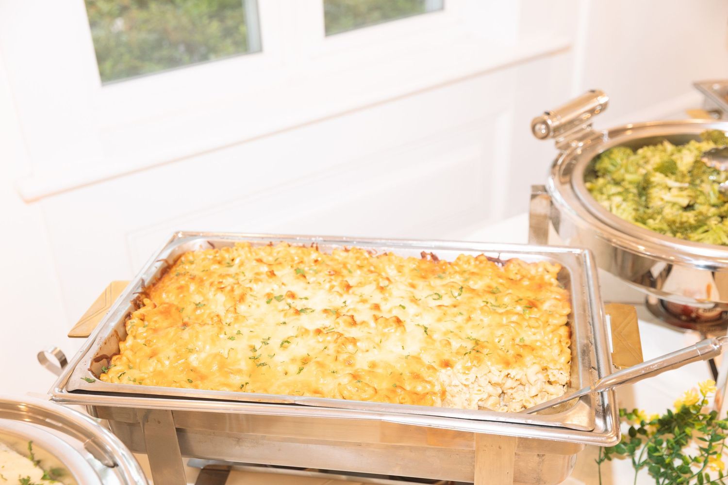 Chafing dish buffet with golden cheesy casserole at an elegant catered event.