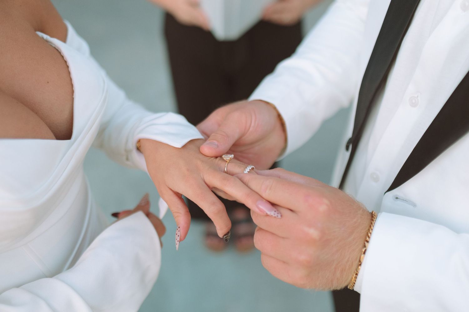 Groom places a wedding ring on brides finger during an intimate ring exchange ceremony closeup.