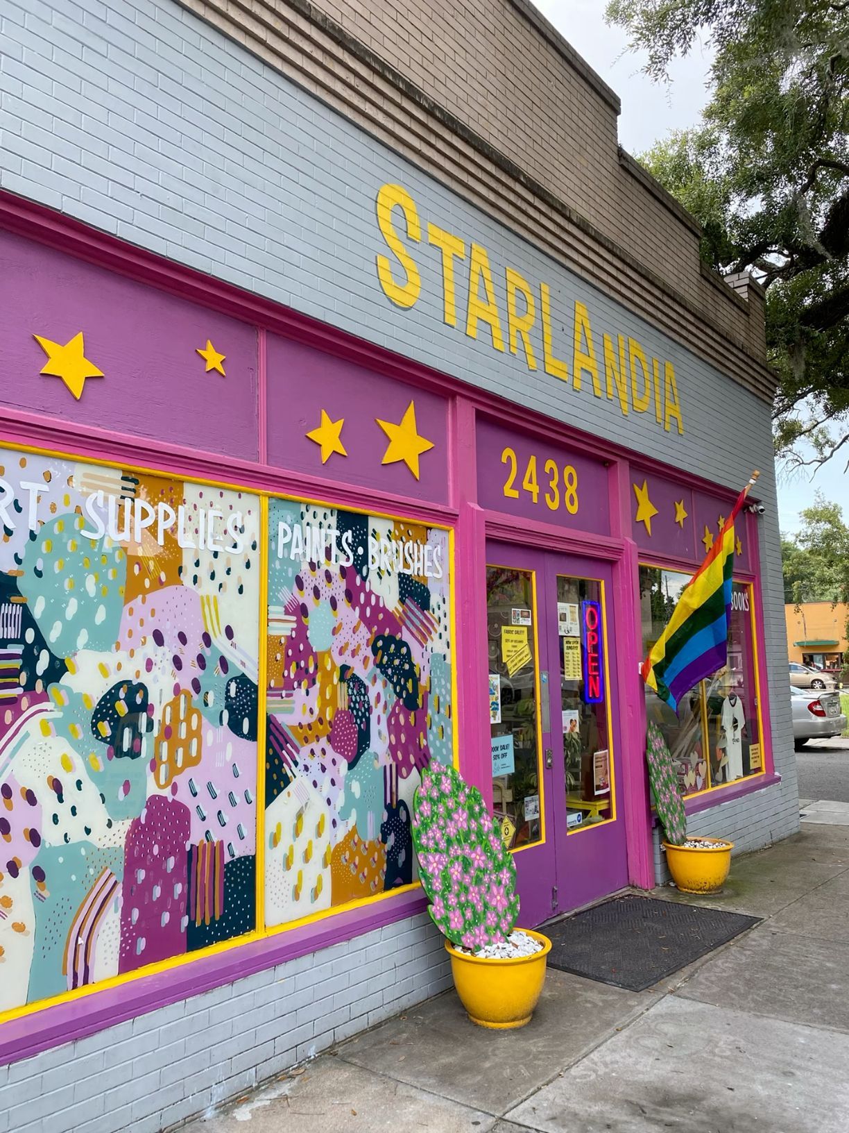 Vibrant storefront of Starlandia at 2438 featuring purple and yellow decor with a pride rainbow flag.