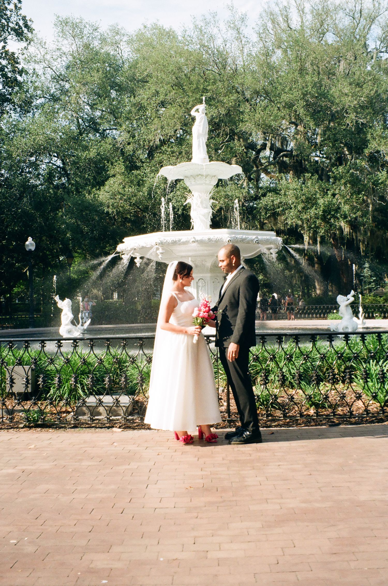 Bride and groom standing before the iconic Forsyth Park fountain in Savannah, Georgia on their wedding day.