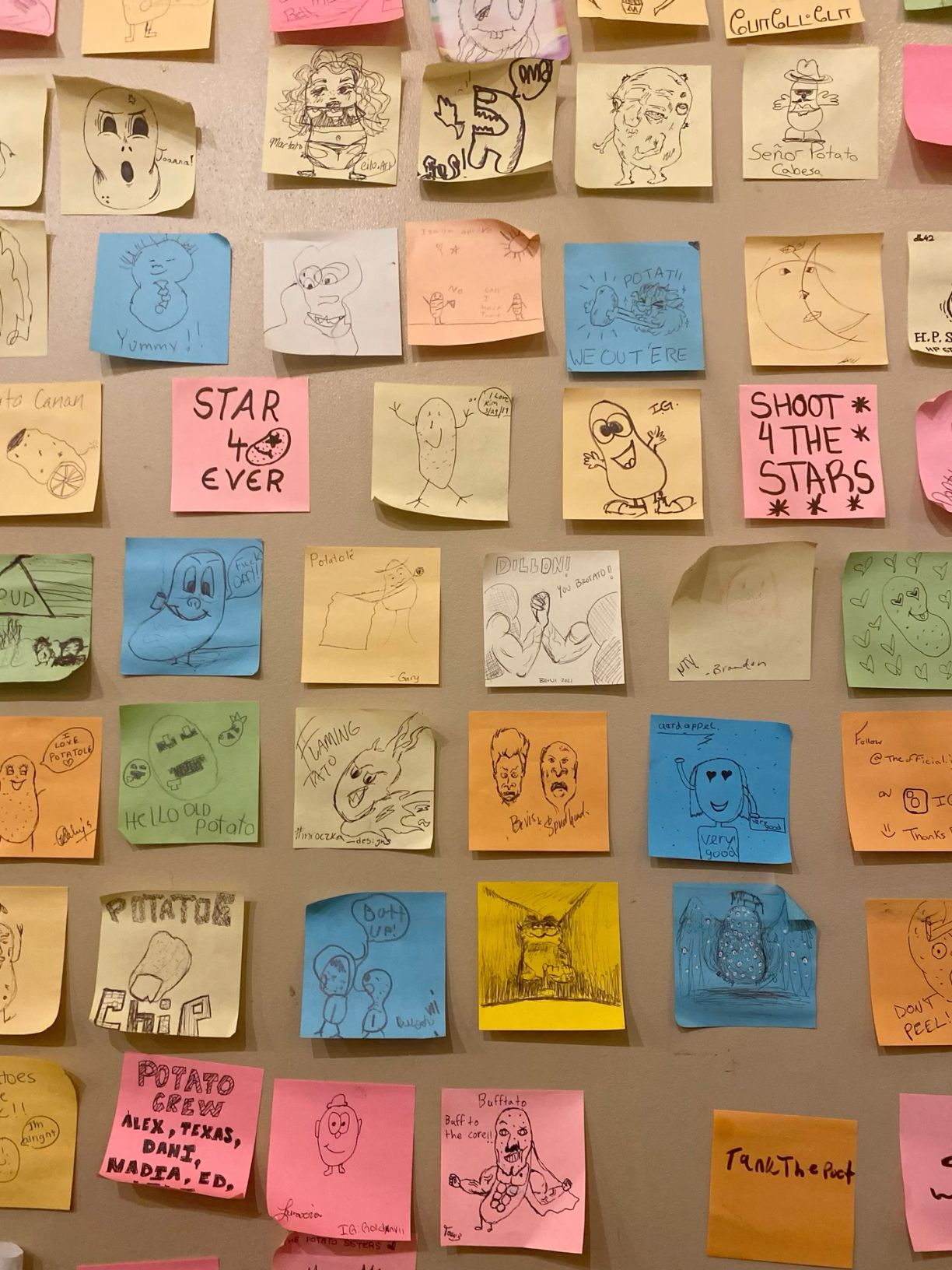 Colorful sticky notes with hand-drawn cartoon doodles and messages covering a wall display.