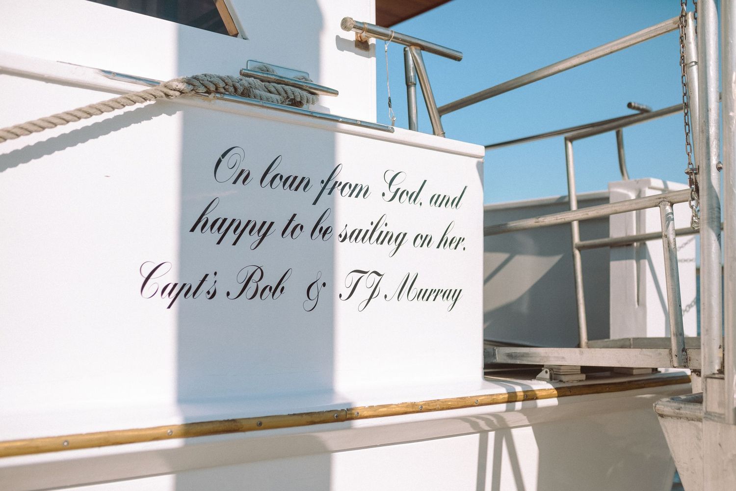 Inspirational quote painted on a white boat hull reading on loan from God by Capts. Bob and T.J. Murray.