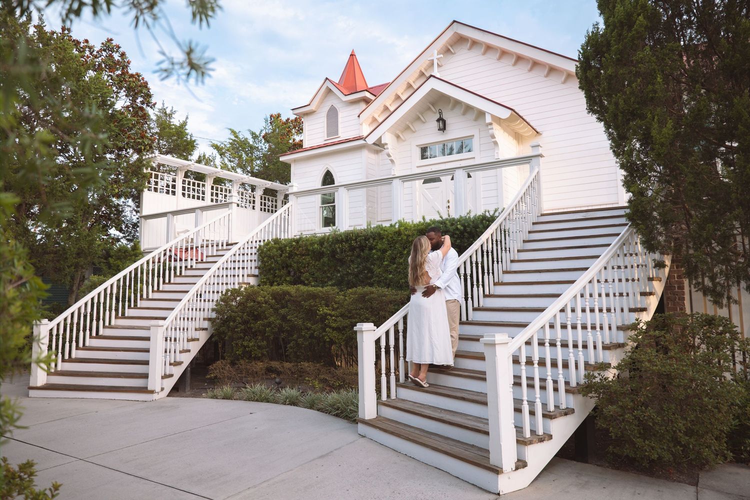 Couple posing on grand white staircase of elegant Victorian-style wedding venue.